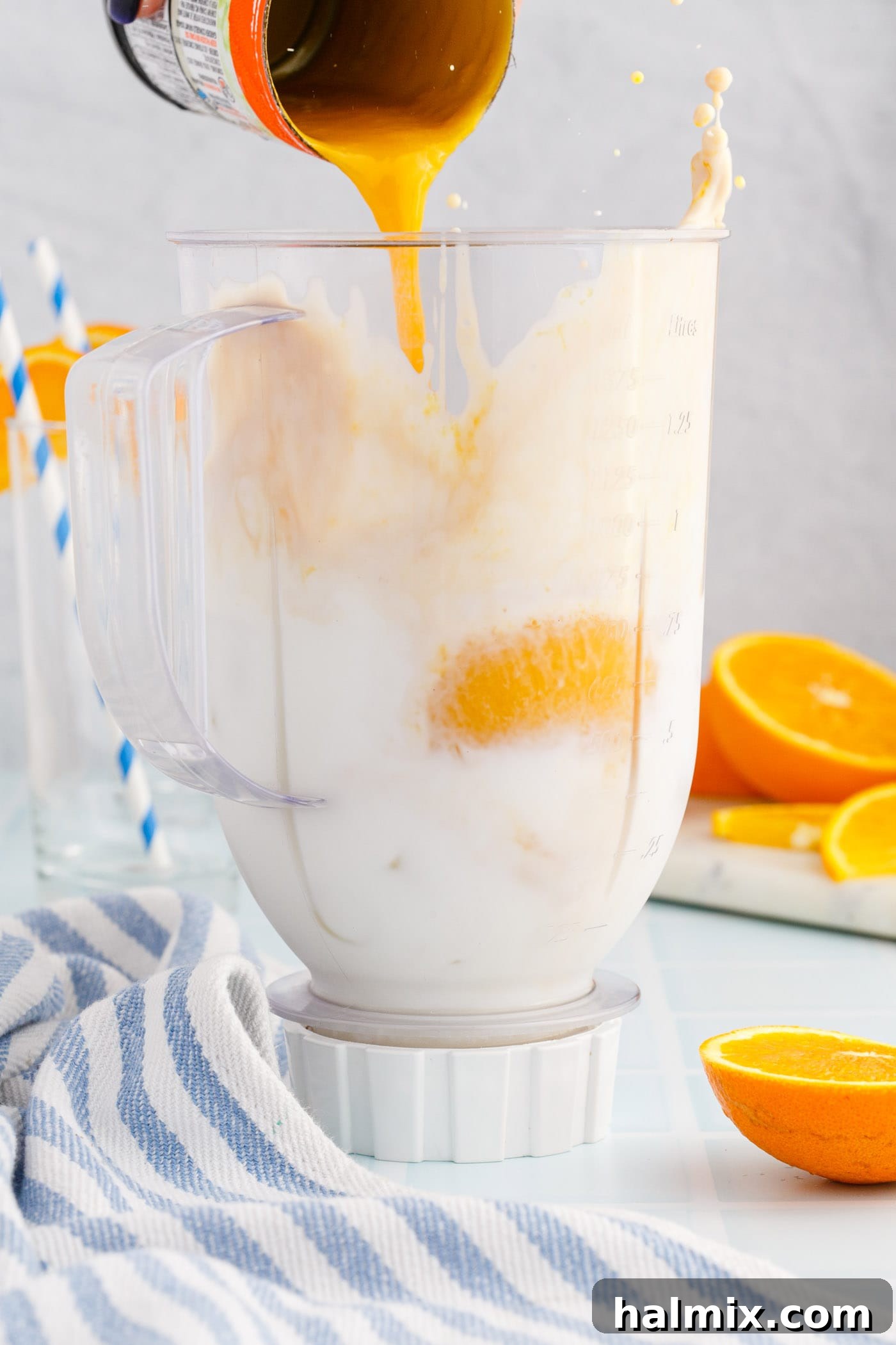 pouring orange julius ingredients into a blender