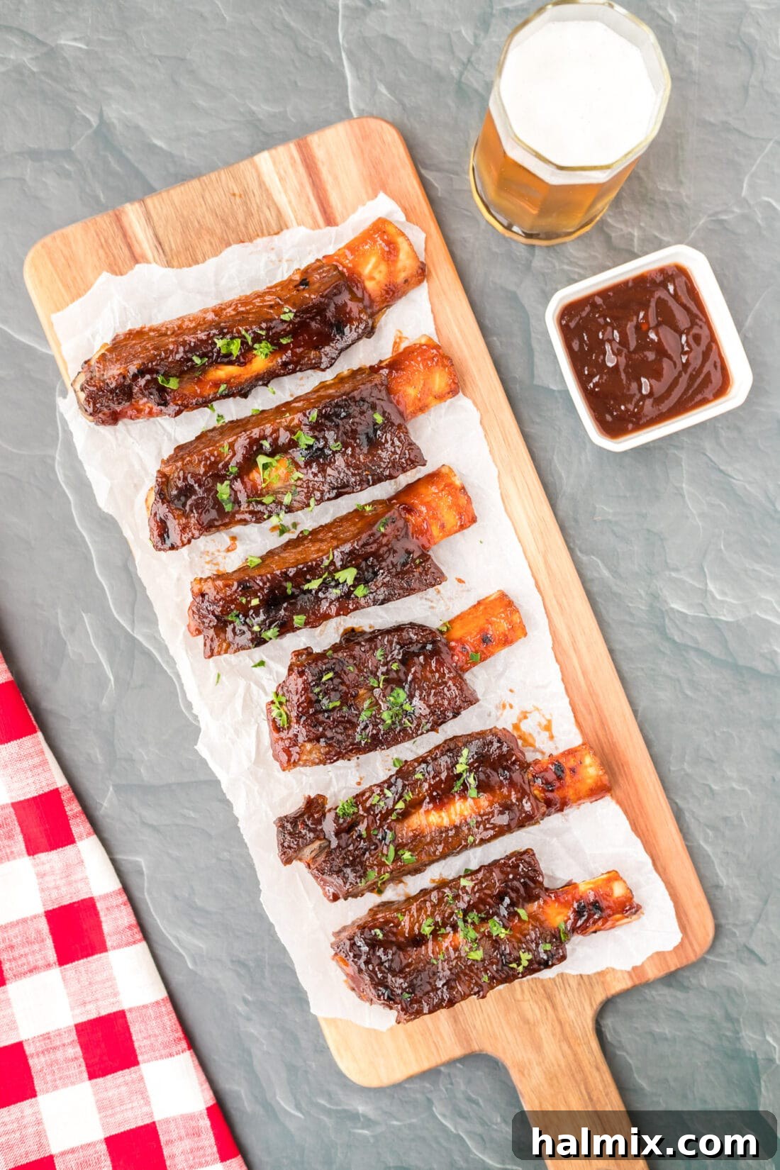 Instant Pot Beef Ribs on cutting board, brushed with barbecue sauce and garnished