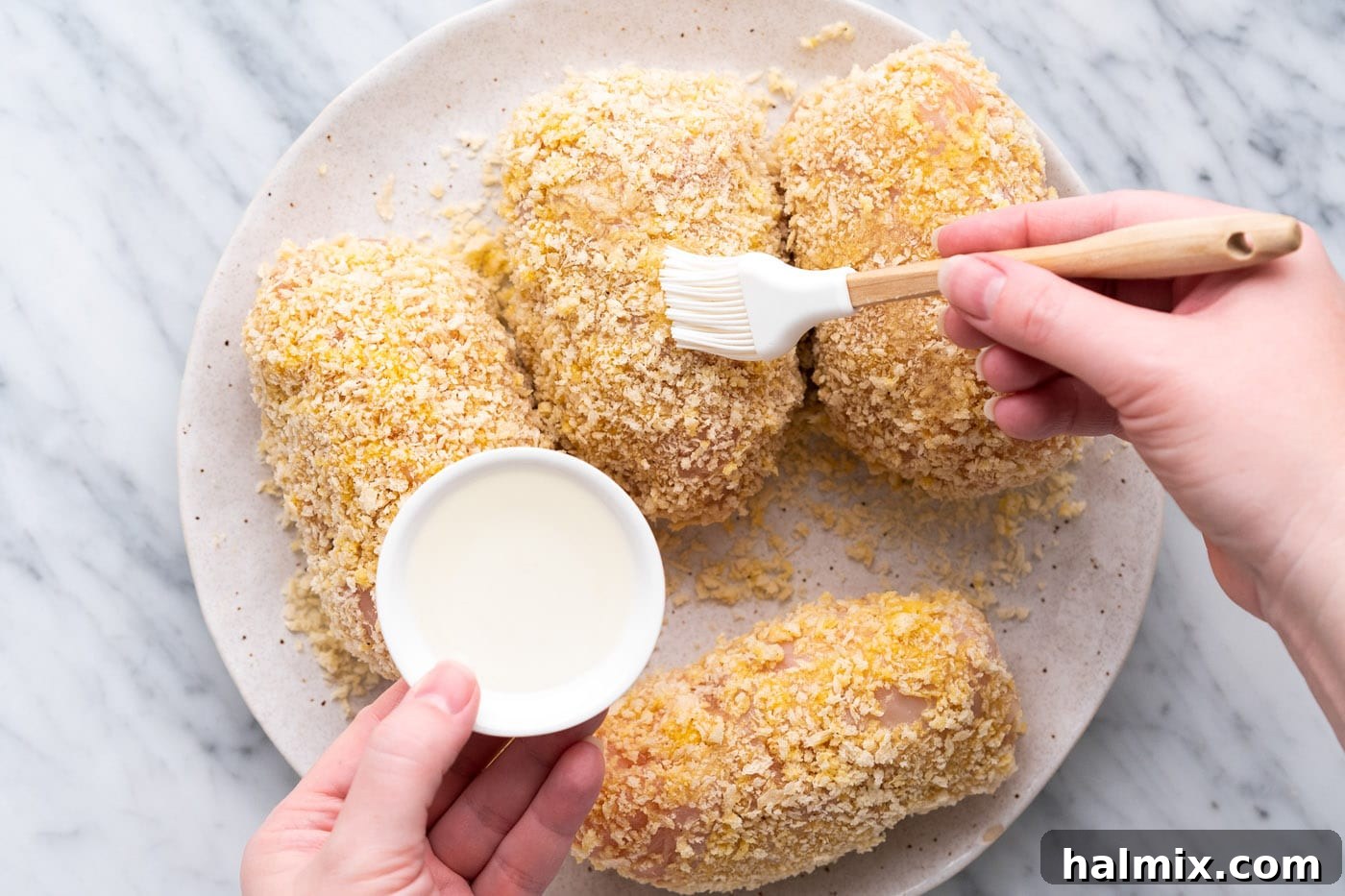 Crispy Air Fryer Chicken Cordon Bleu 13 Brushing vegetable oil onto the breaded chicken cordon bleu before air frying.