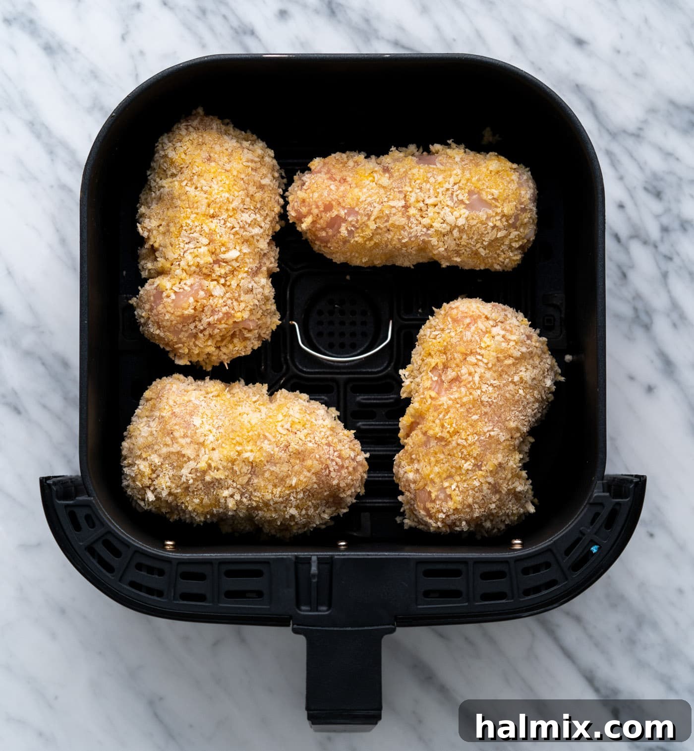 Crispy Air Fryer Chicken Cordon Bleu 14 Chicken cordon bleu cooking in the basket of an air fryer.