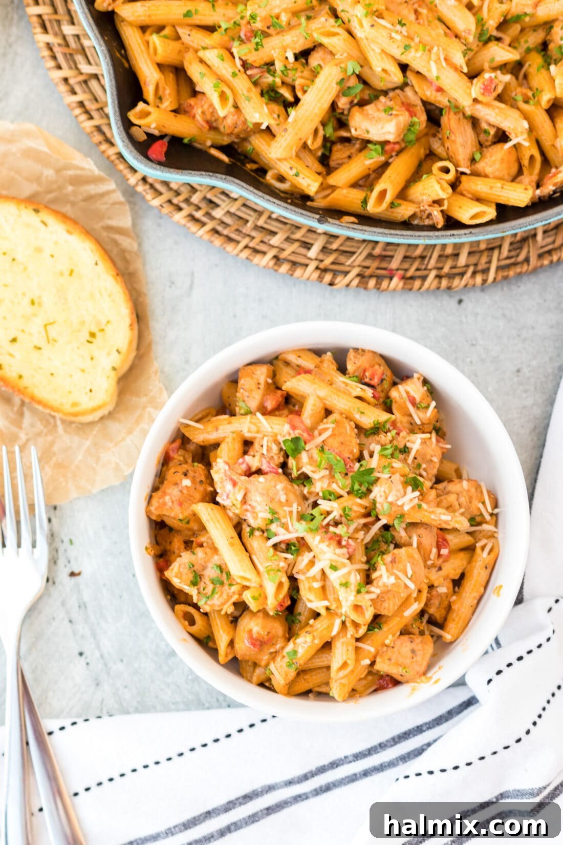 A close-up shot of a bowl filled with creamy Cajun Chicken Pasta, garnished with fresh parsley and grated Parmesan cheese.