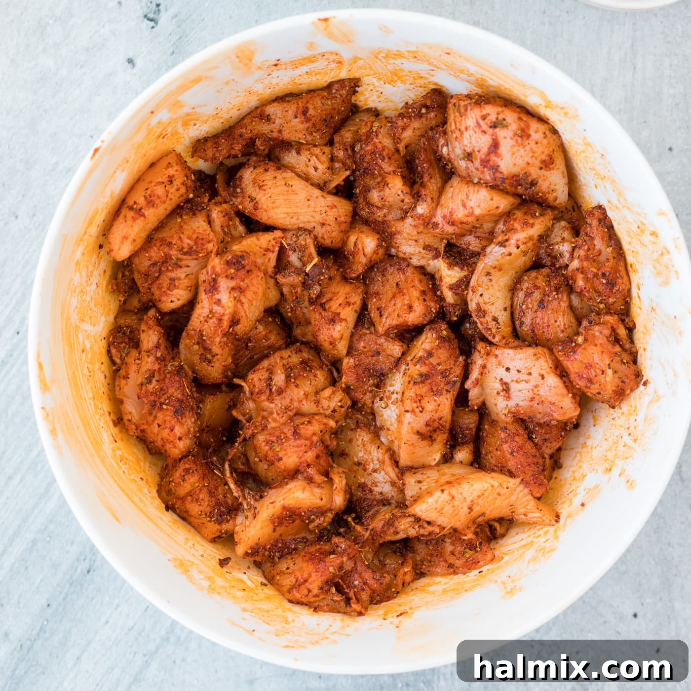 Cajun seasoned chicken pieces in a bowl, ready to be cooked.