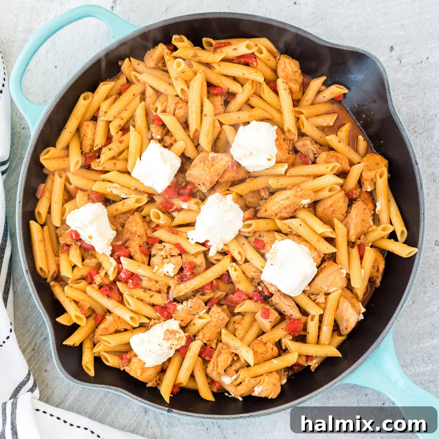 Cajun chicken pasta in a skillet with cream cheese melting into the sauce.