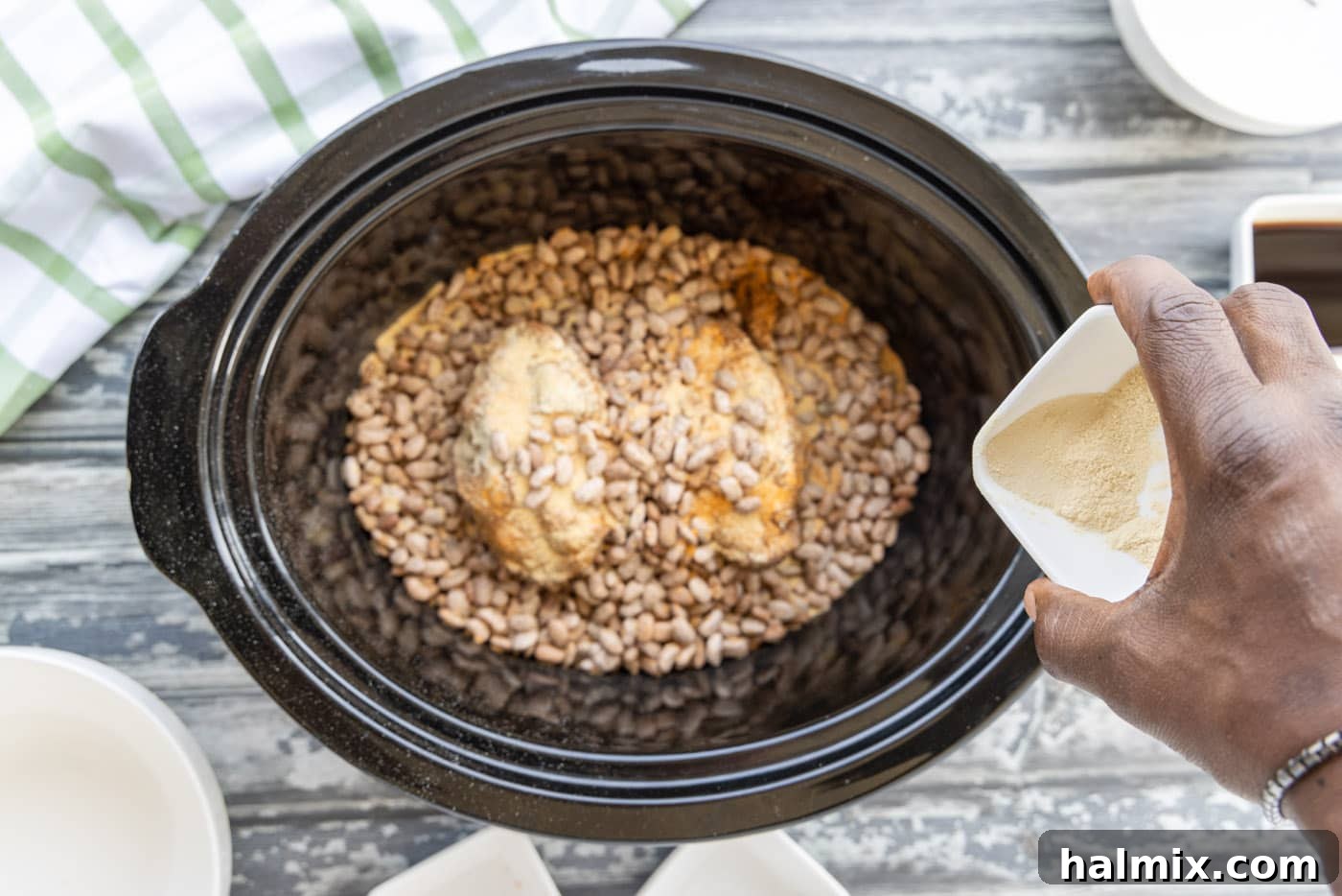 Adding the final layer of pinto beans on top of turkey tails and seasoning