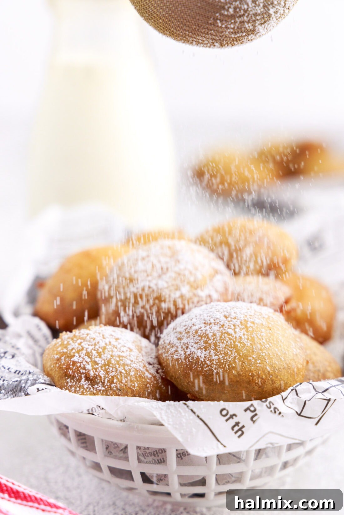 Sweet Crispy Fried Oreos 3 A close-up shot of a hand gently dusting homemade Fried Oreos with a cloud of powdered sugar, creating a beautiful sweet finish on the warm treats.