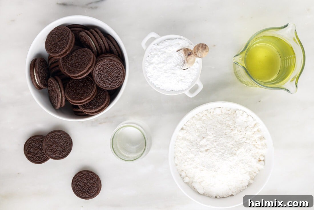Sweet Crispy Fried Oreos 4 A perfectly arranged flat lay showcasing all the simple ingredients required to make Fried Oreos at home: a package of Oreos, a bowl of pancake mix, a glass of water, a bottle of vegetable oil, and a small bowl of powdered sugar.