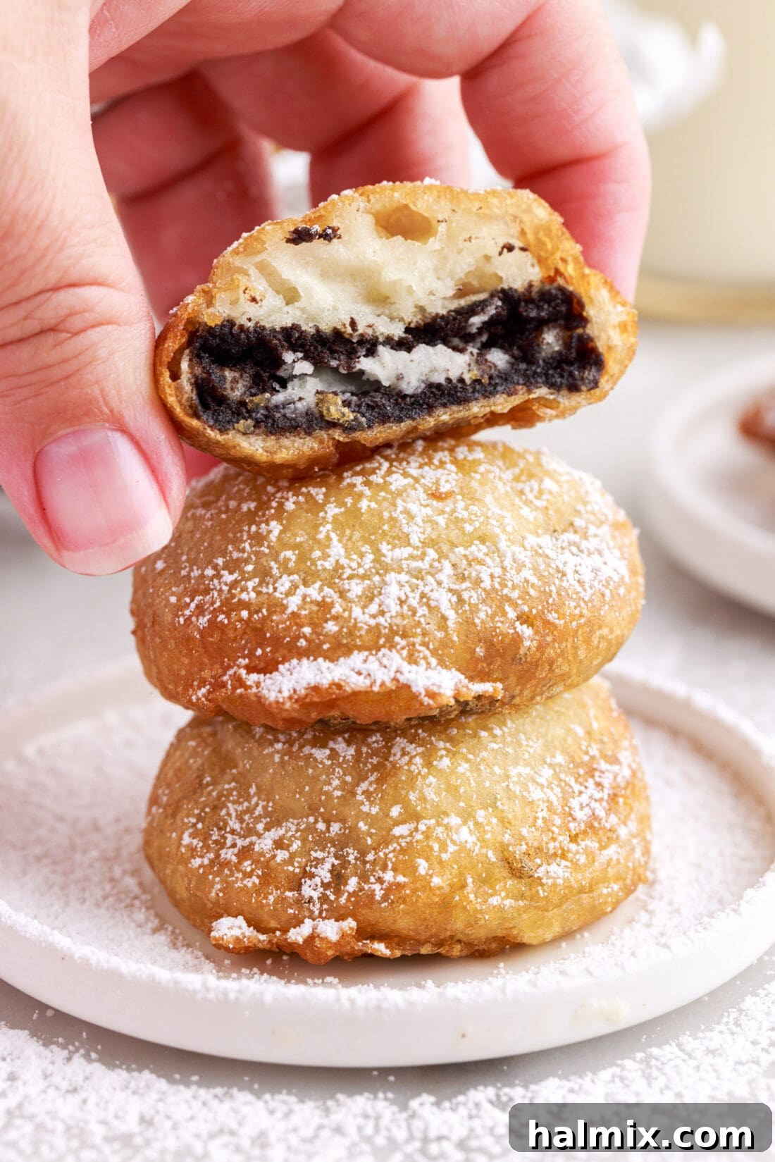 Sweet Crispy Fried Oreos 5 A beautifully arranged stack of golden-brown homemade Fried Oreos, generously dusted with powdered sugar, sitting on a pristine white serving plate.