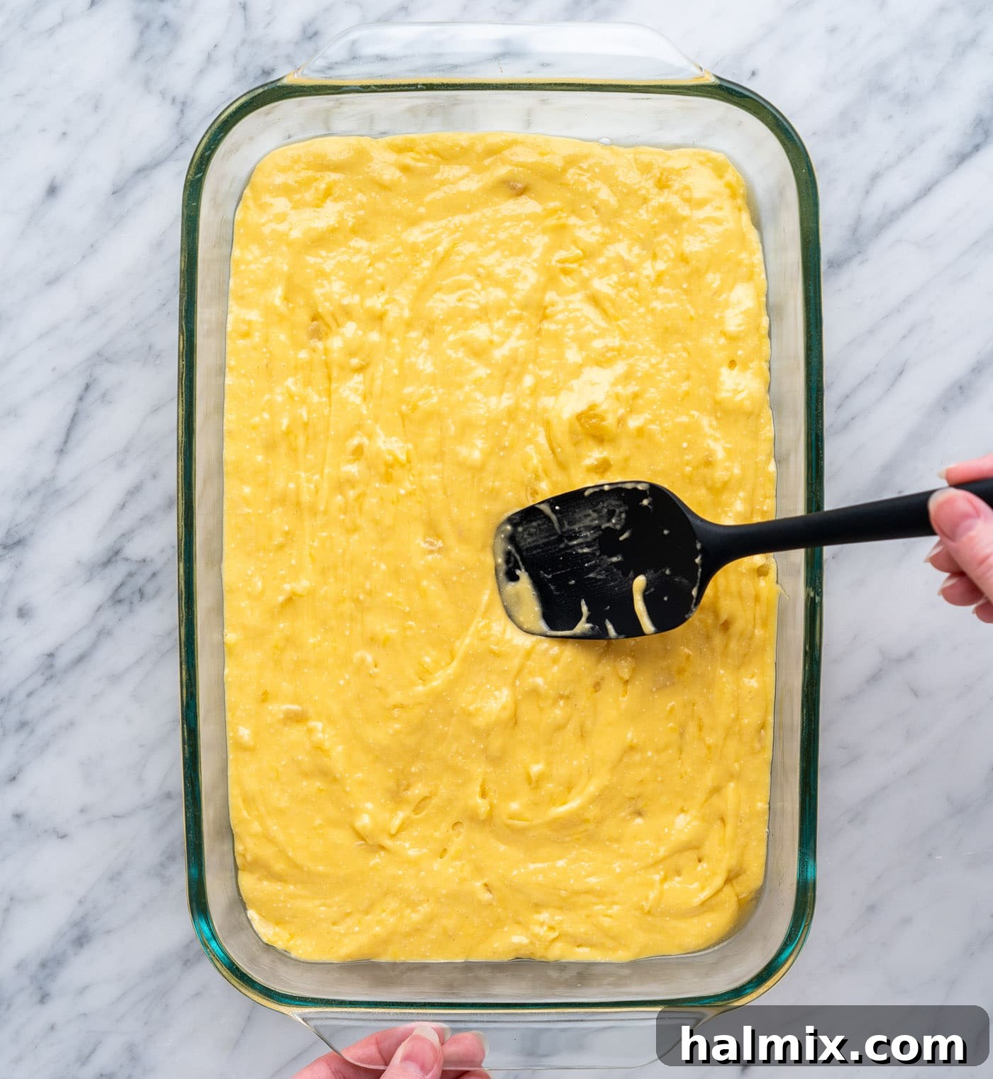 Sun-Kissed Pineapple Dream 8 spreading pineapple cake batter into a baking dish evenly, ensuring a flat top
