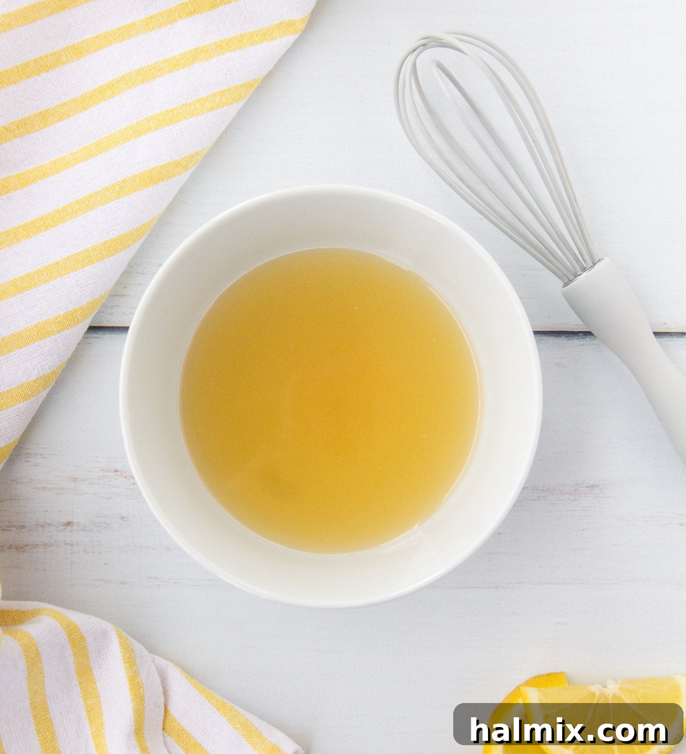 Honey, salt, and brown sugar being whisked into lemon juice in a glass mixing bowl.