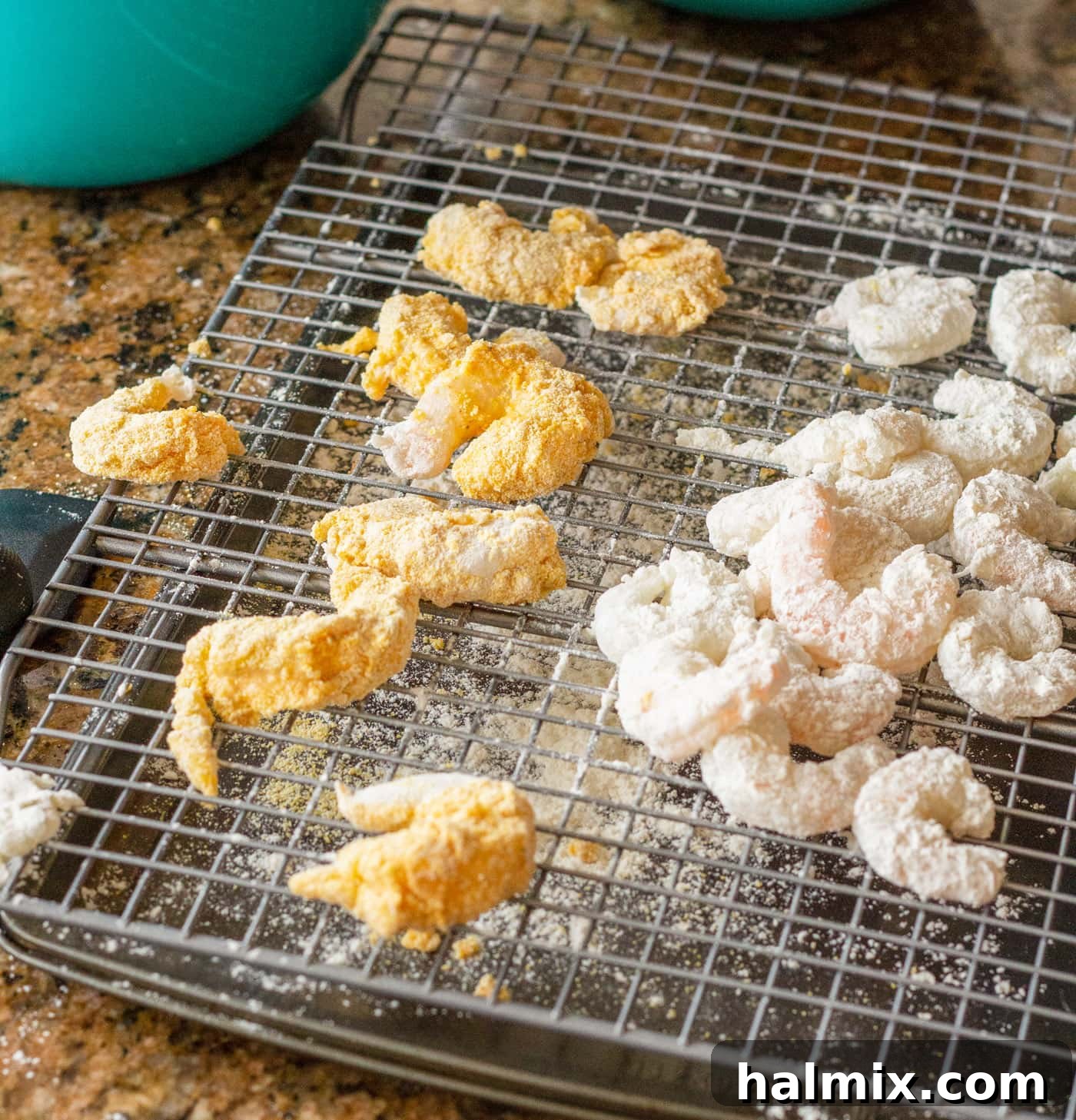 Breaded shrimp resting on a wire cooling rack before frying, ensuring the coating sets.