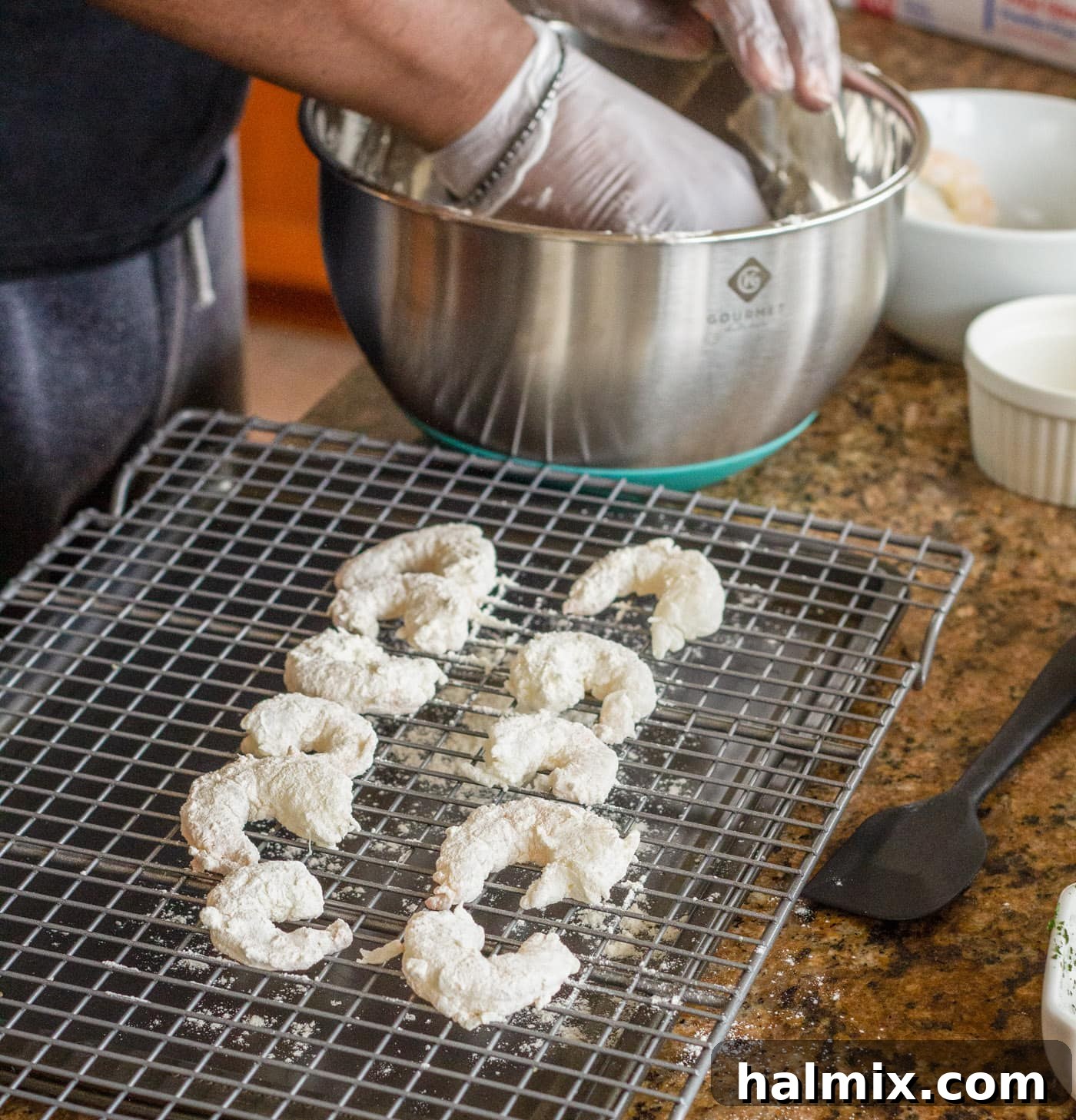 Flour-coated shrimp resting on a wire rack, ready for the next step in breading.
