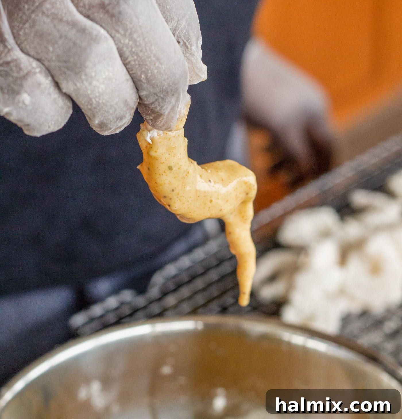 Dipping a flour-dredged shrimp into the seasoned egg mixture.