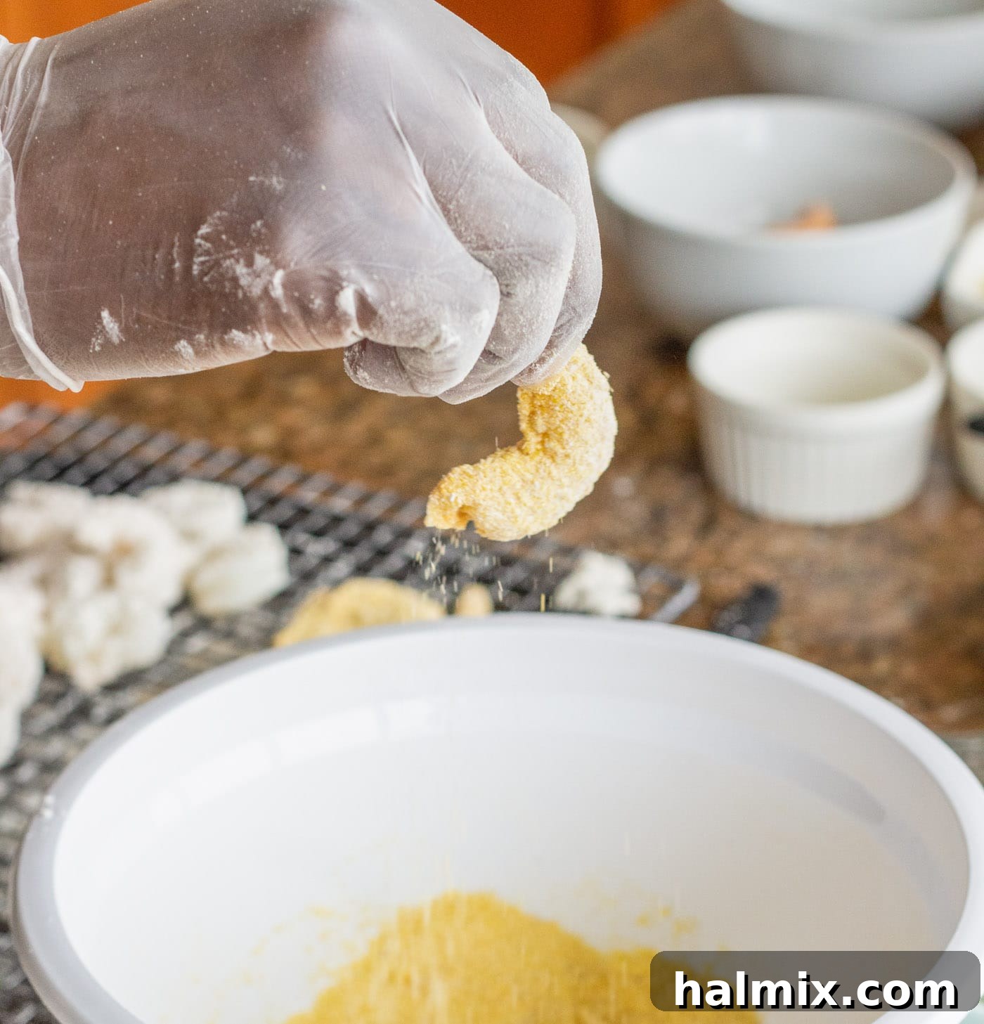 Coating a shrimp, already dipped in egg, into the cornmeal mixture for its final breading layer.