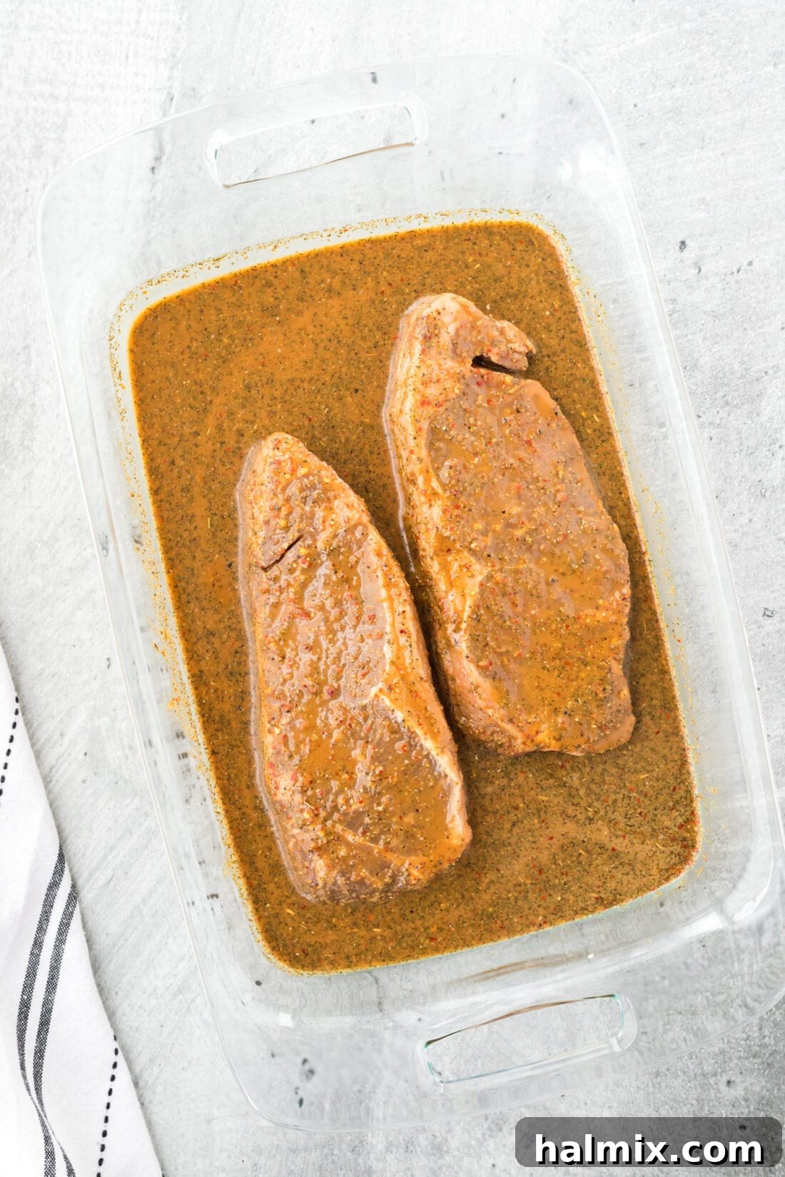 The Ultimate Steak Upgrade 2 Raw steak marinating in a savory sauce in a glass pan, promising tender, flavorful results.