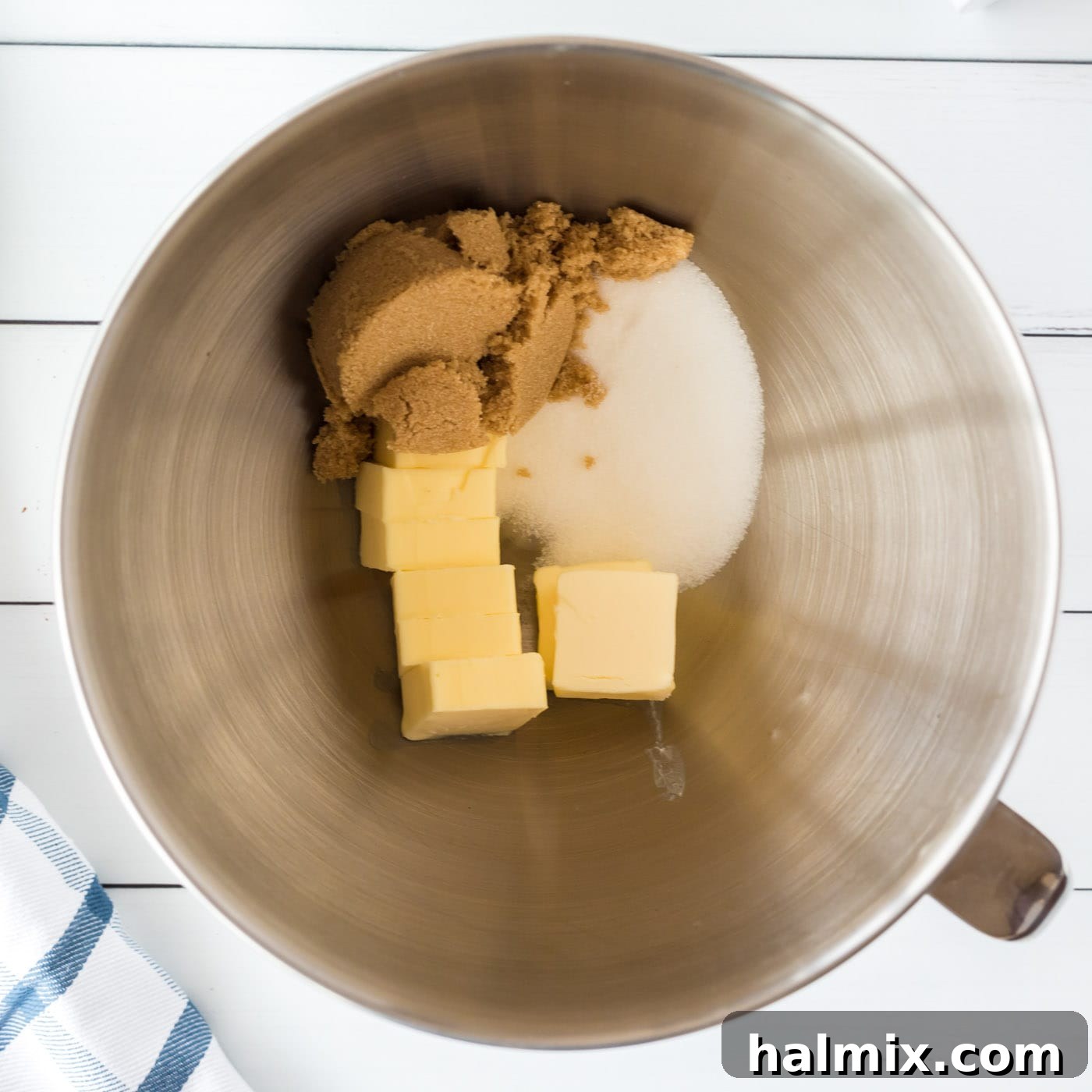 Softened butter and two types of sugar (granulated and brown) creaming together in a mixer bowl