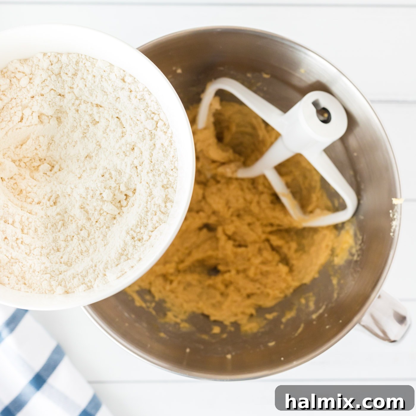 Gradually adding the whisked flour mixture into the cookie dough in a mixing bowl