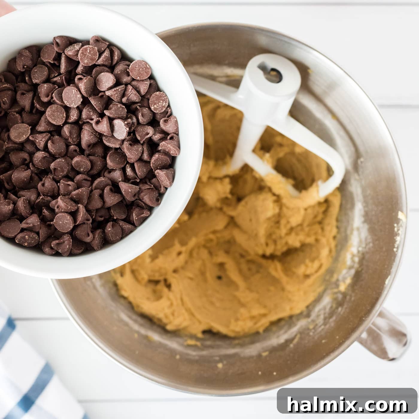 Semi-sweet chocolate chips being folded into the chewy cookie dough with a spatula