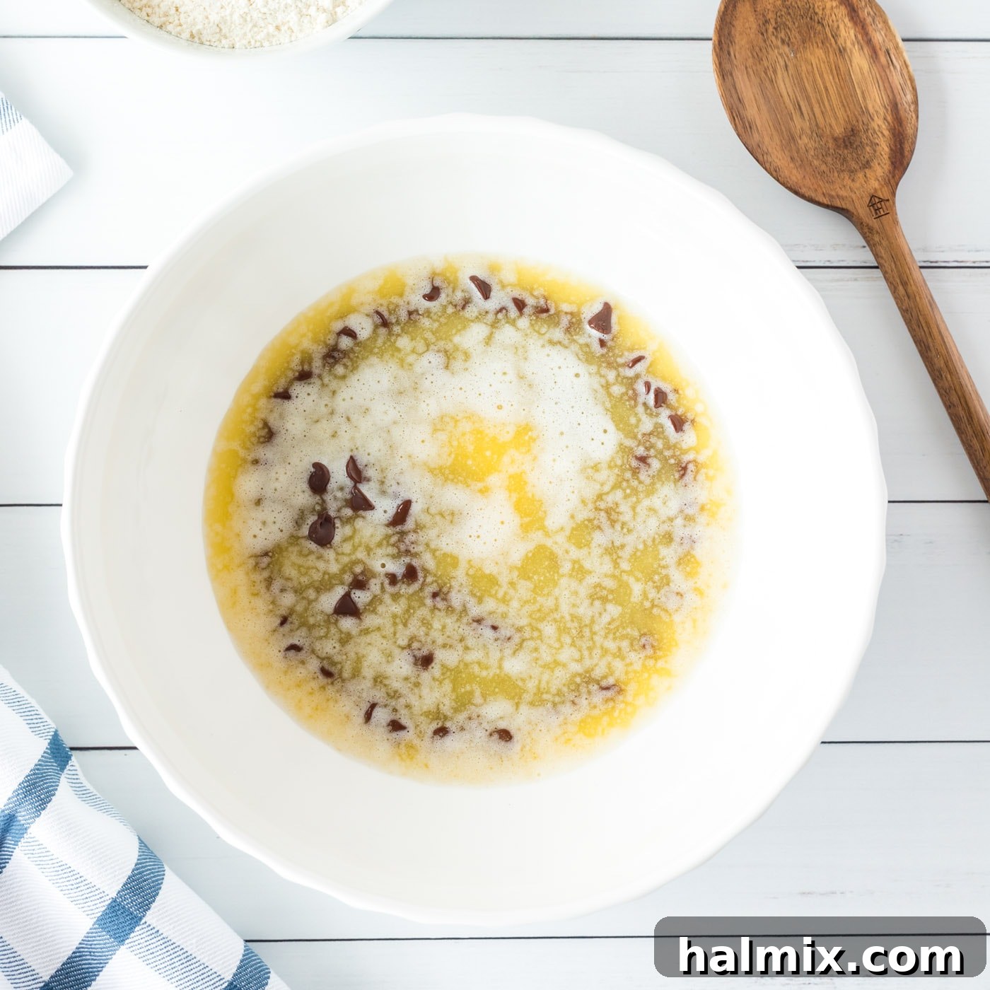 Melted butter poured over semi-sweet chocolate chips in a large mixing bowl, resting to soften
