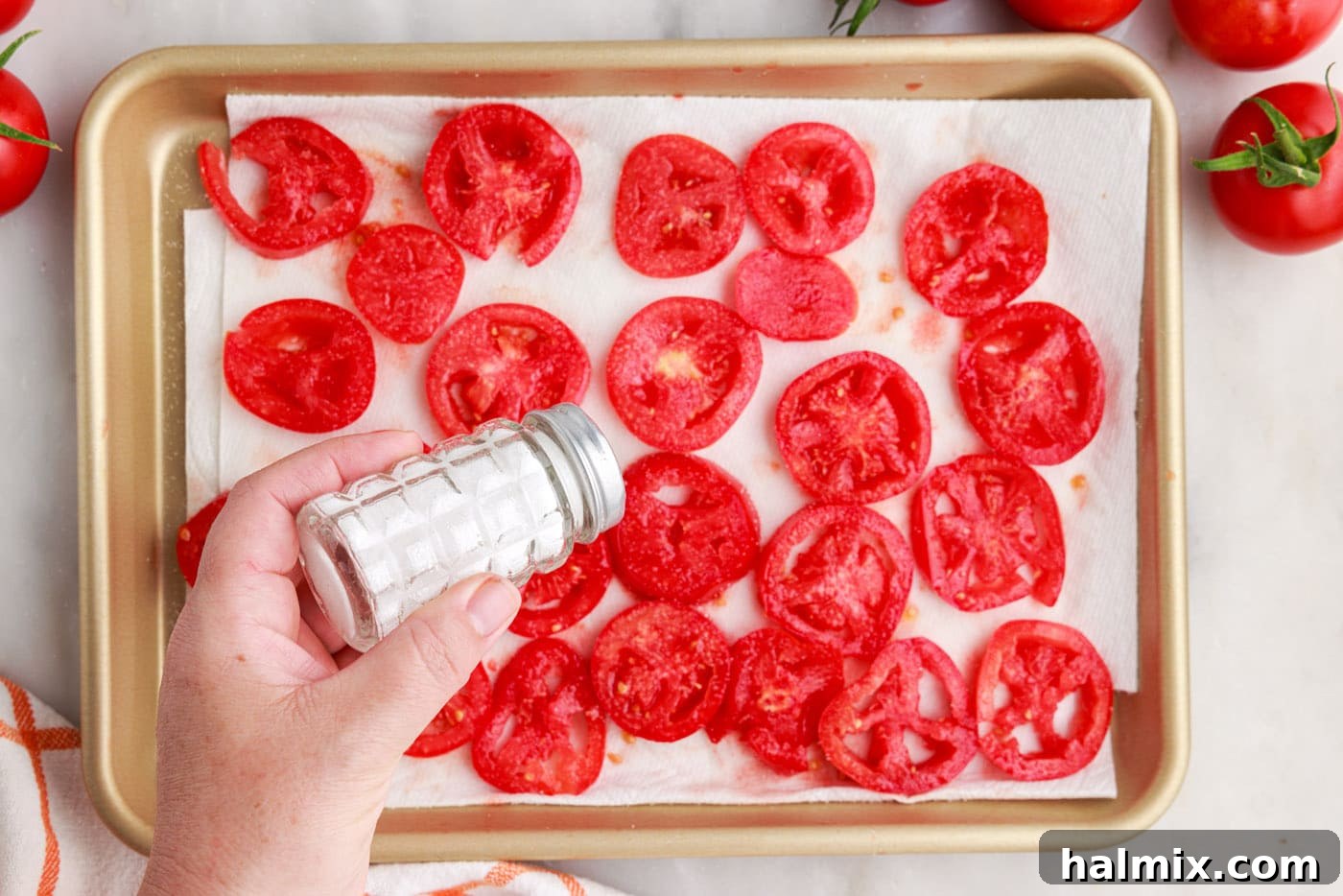 salting tomatoes on a pan for tomato pie