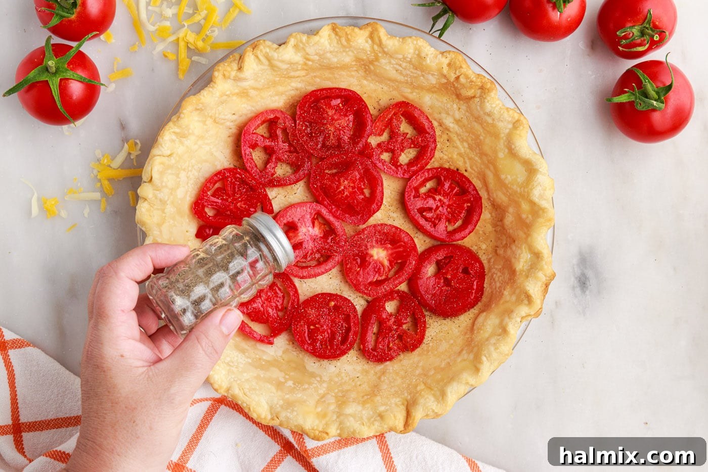 sprinkling black pepper on top of tomato pie