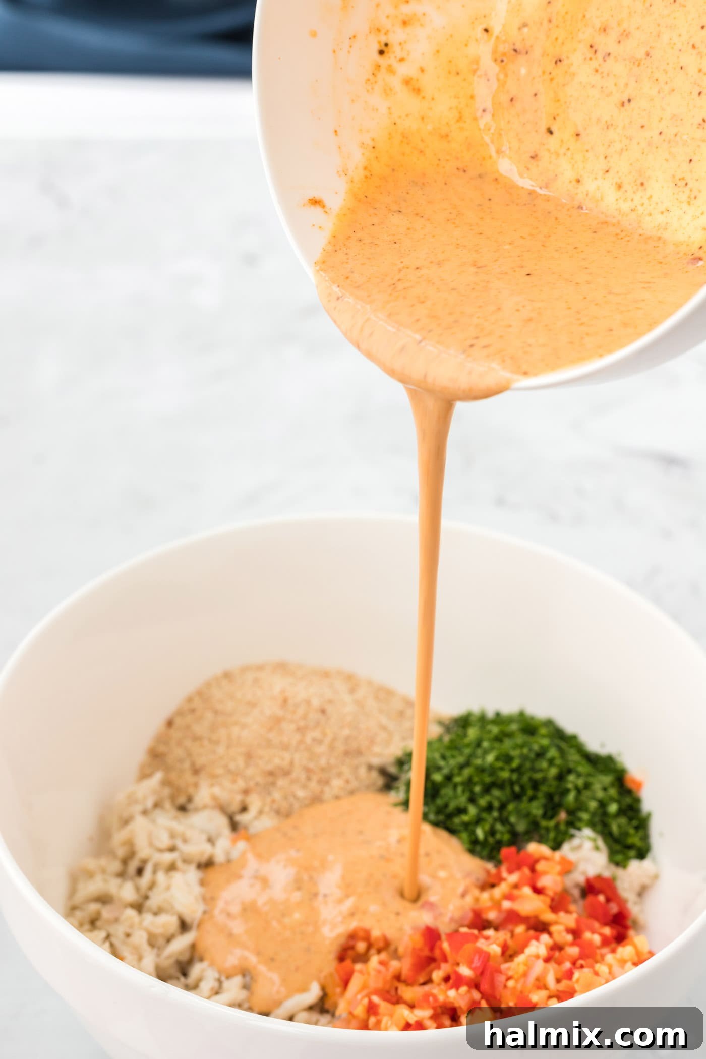 Golden Crab Delights 6 pouring sauce over crab cake mixture in a bowl