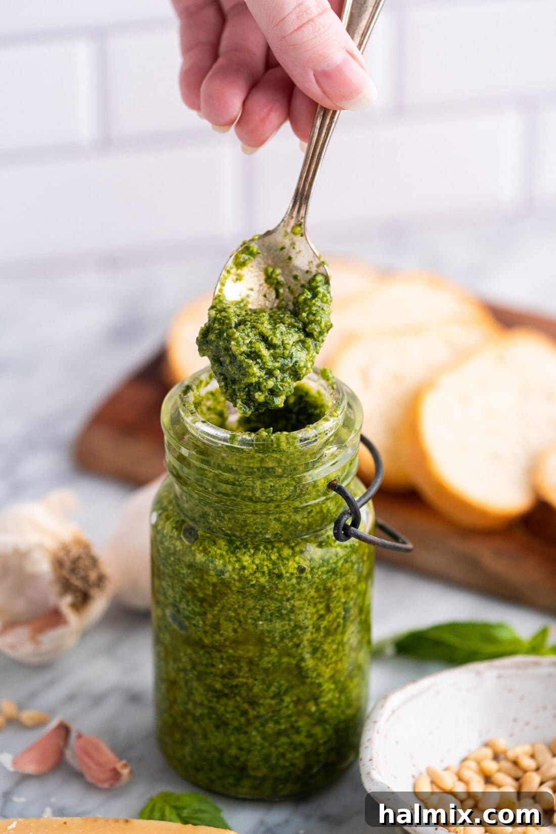 Homemade basil pesto stored in a glass jar, topped with a thin layer of olive oil to preserve freshness.