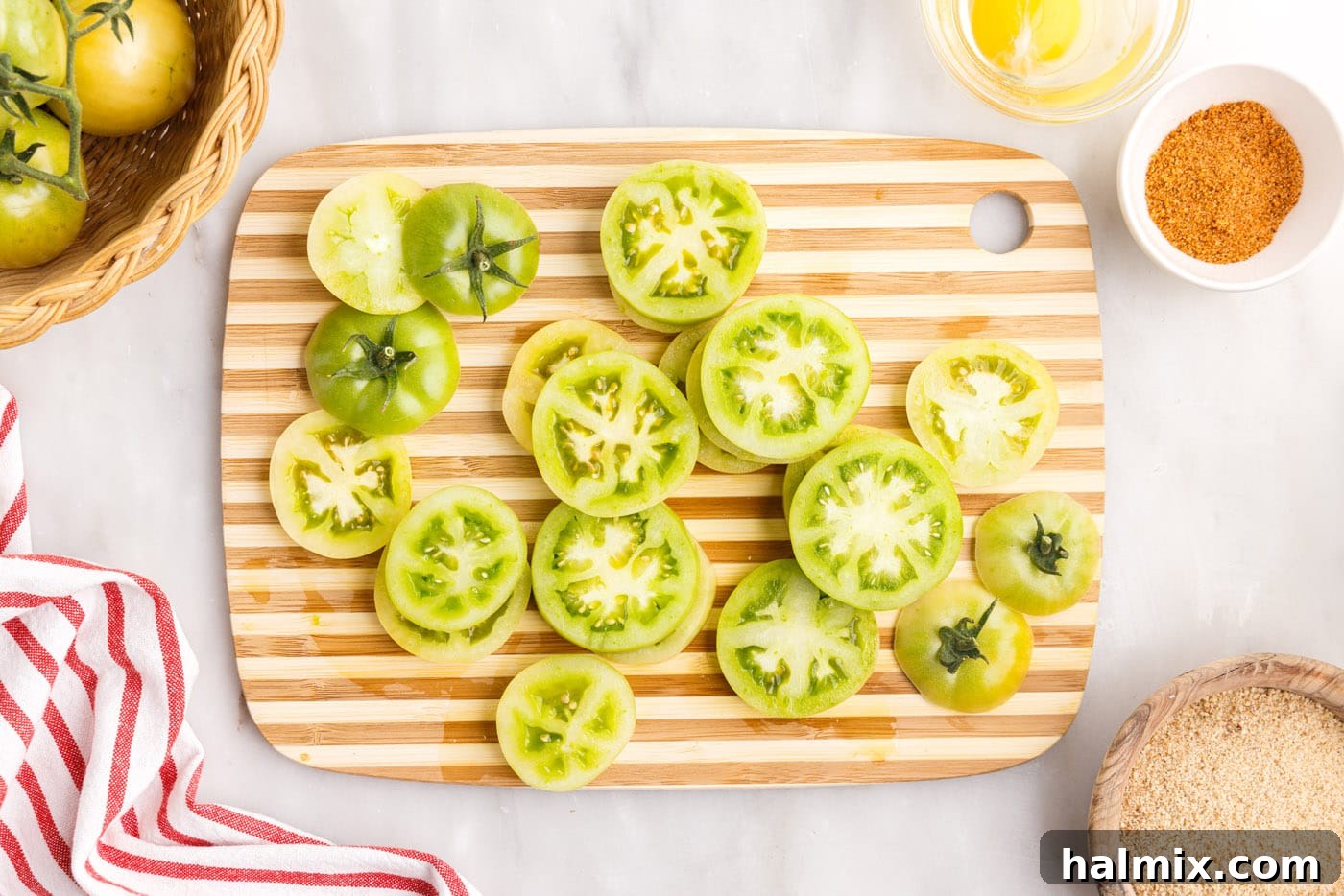 Sliced green tomatoes arranged on a cutting board, ready for moisture removal
