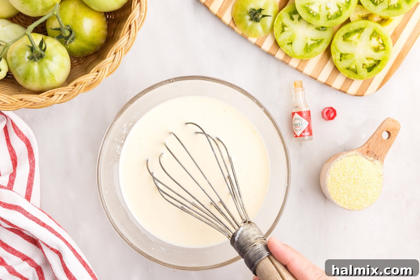 A bowl containing milk, whisked egg, and a splash of Tabasco sauce being combined