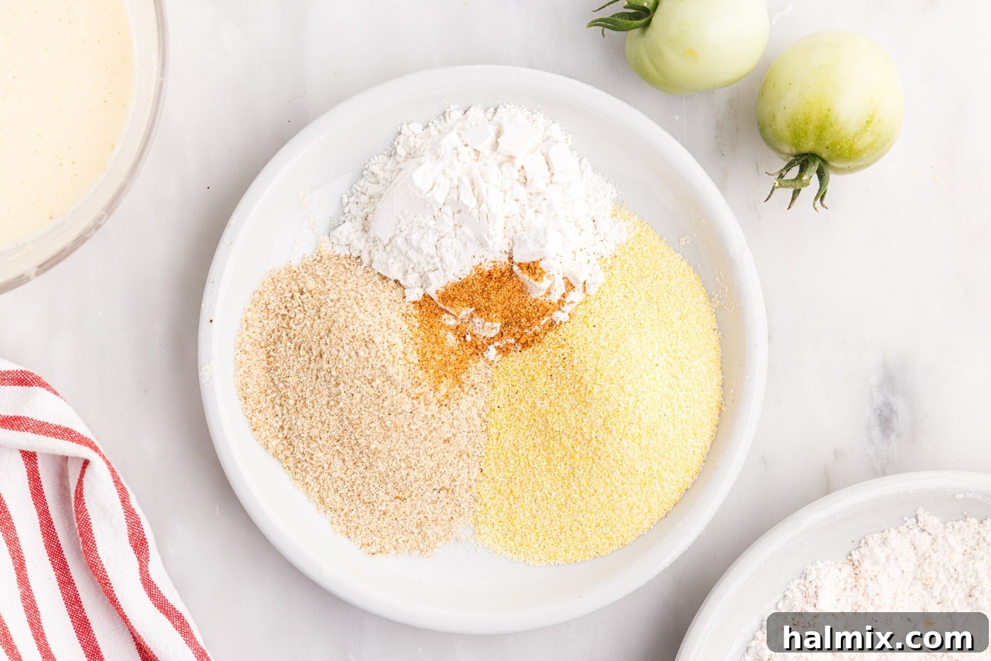 Separate bowls displaying flour, cornmeal, Cajun seasoning, and breadcrumbs before mixing