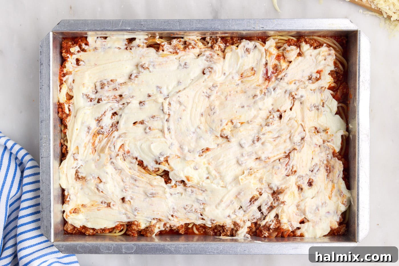 Creamy ricotta cheese mixture dolloped and spread over the meat sauce and spaghetti, adding a rich, cheesy layer.