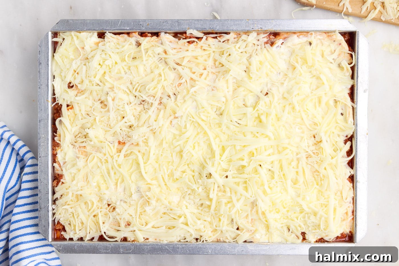 Generous layers of grated mozzarella and Parmesan cheese covering the top of the Million Dollar Spaghetti casserole before baking.