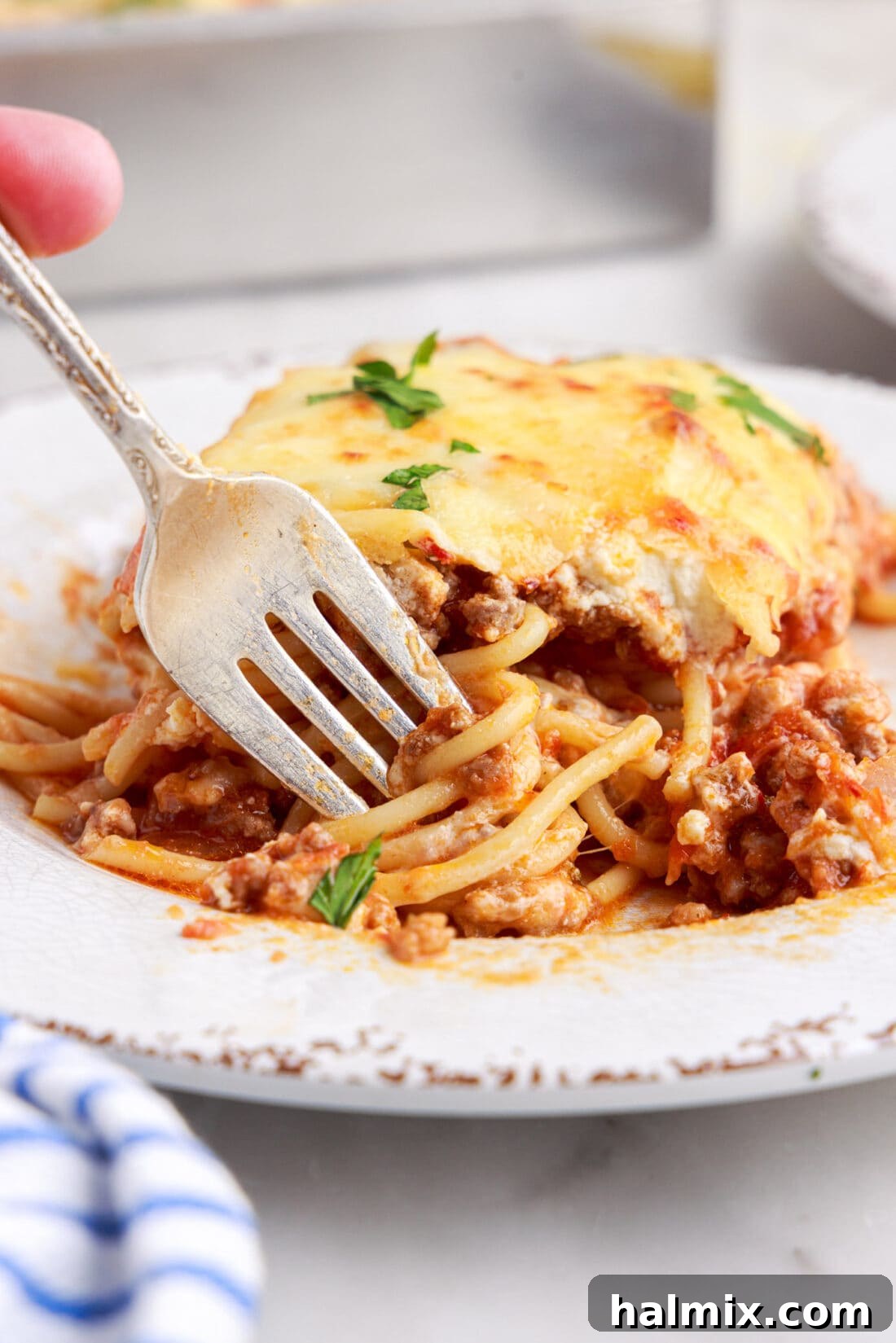 A perfectly portioned plate of Million Dollar Spaghetti casserole, showcasing its golden-brown cheesy top and rich internal layers.