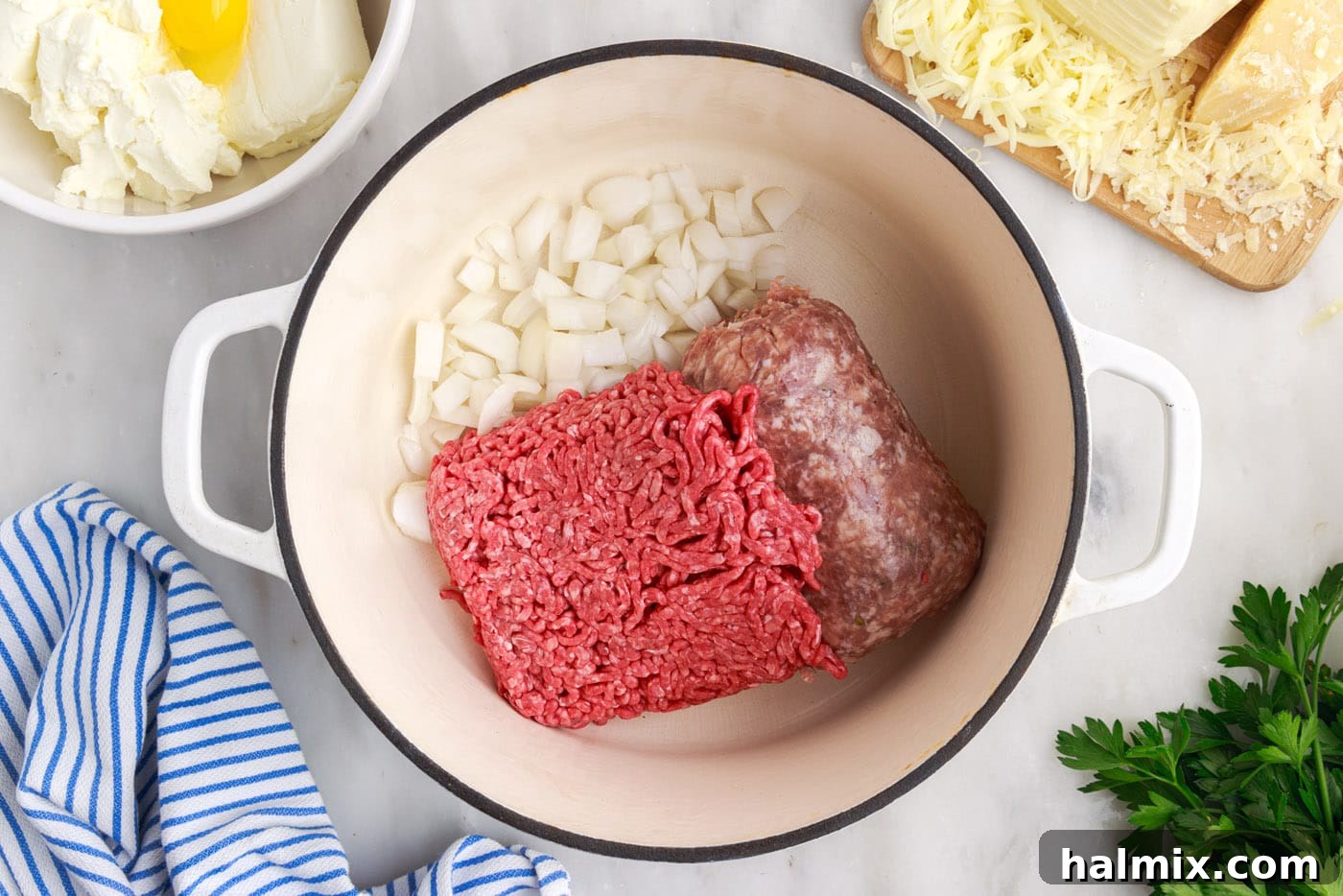 Italian sausage and ground beef cooking in a skillet with chopped onions, browning evenly.