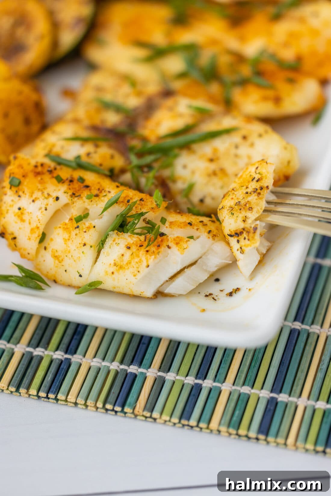 A fork holding a piece of flaky baked orange roughy, showcasing its tender texture