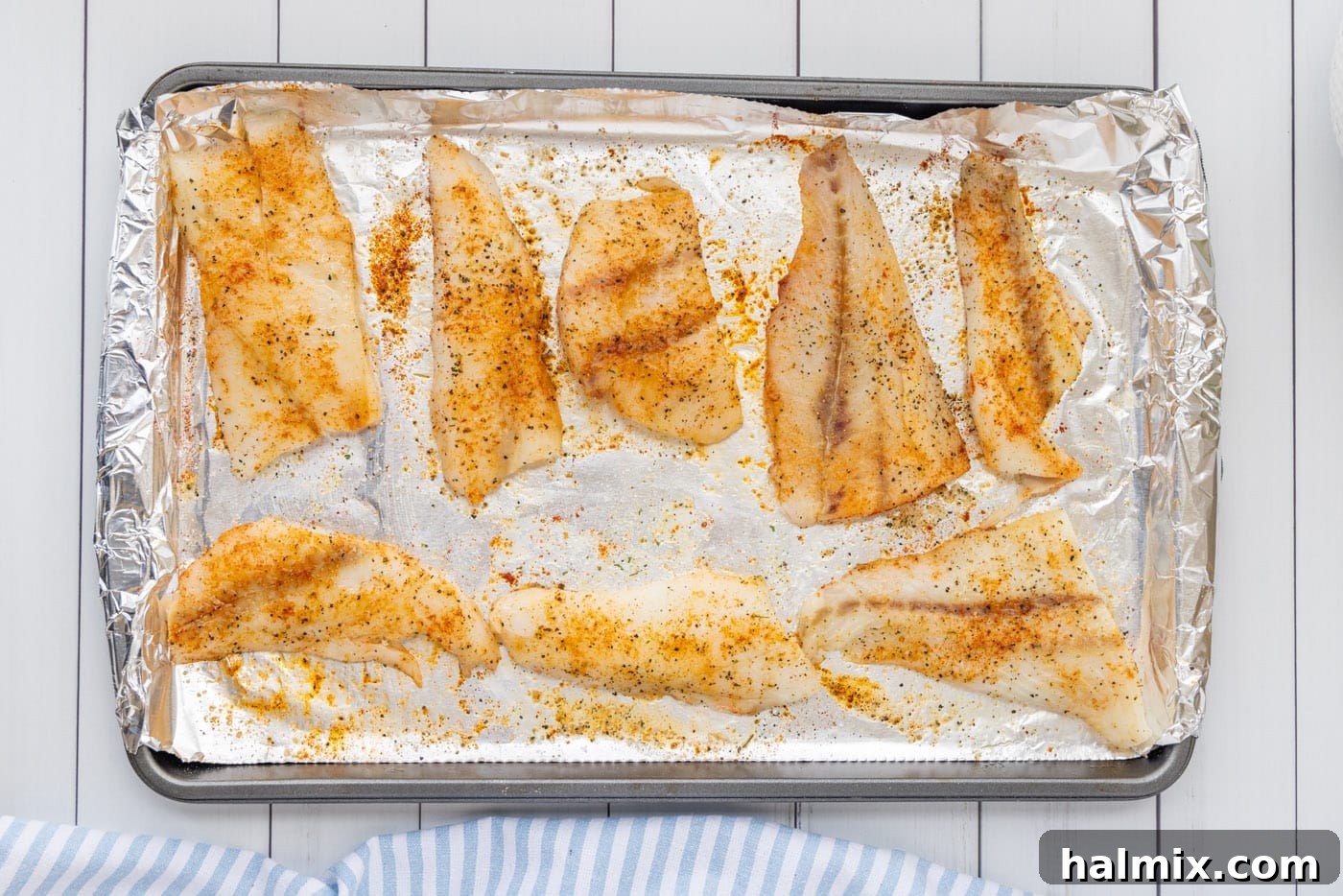 Seasoned orange roughy fillets arranged on a foil-lined baking sheet, ready for the oven
