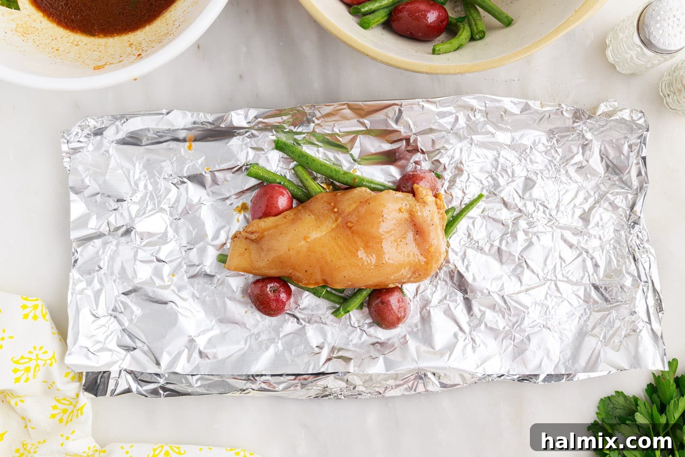 Easy Campfire Foil Meals 9 Marinated chicken placed over green beans and potatoes in a foil packet