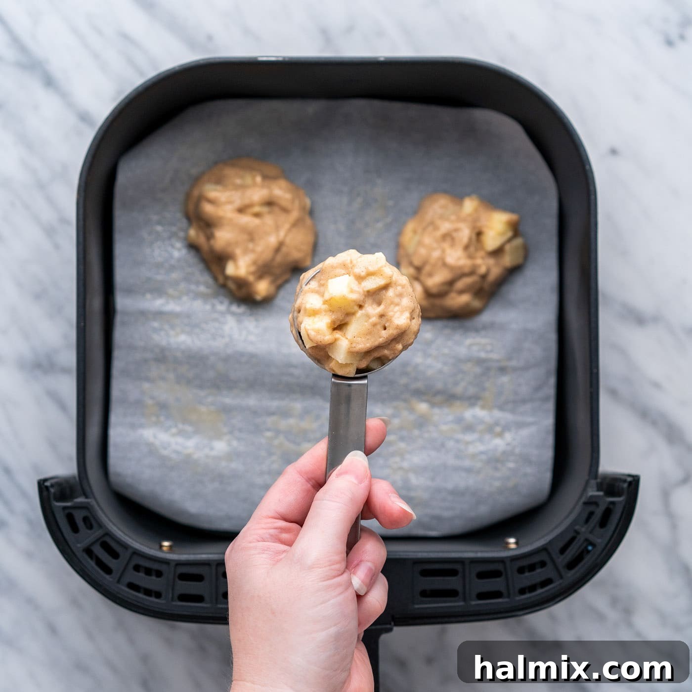 scoop of apple fritter batter over air fryer basket