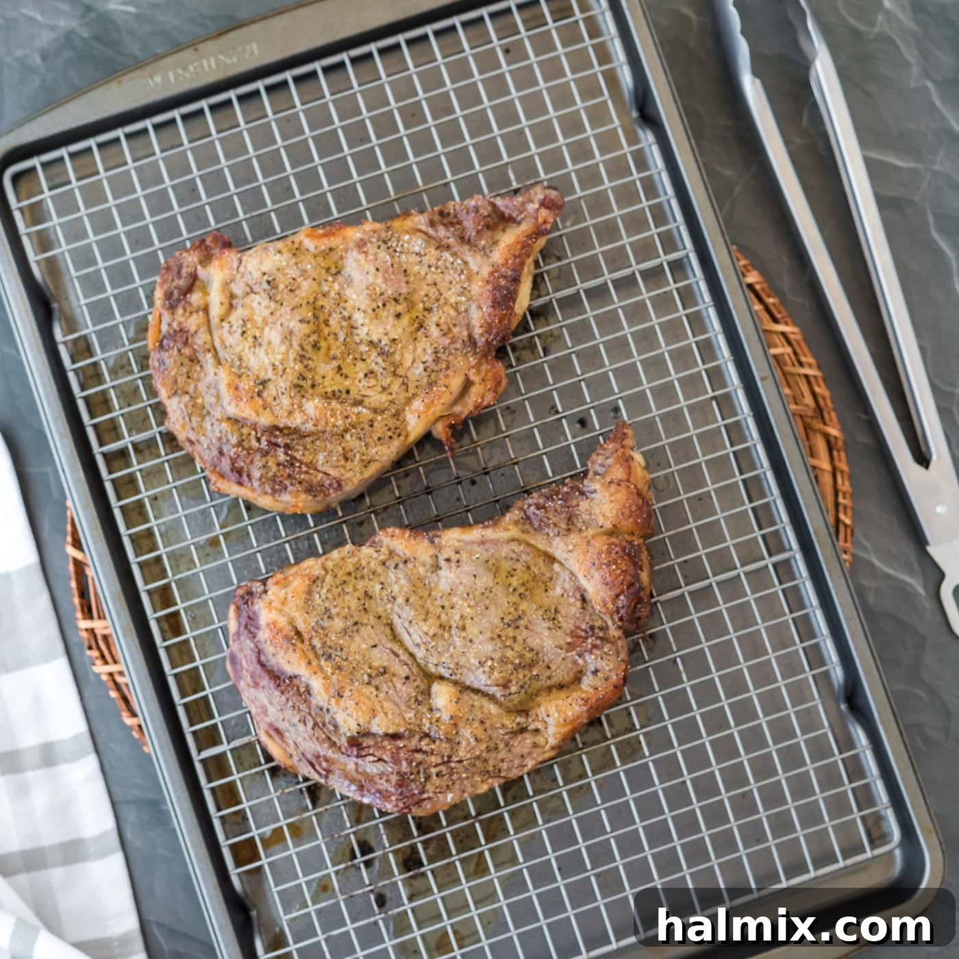 Baked ribeye steak, still on the wire rack, showing a lightly browned surface.