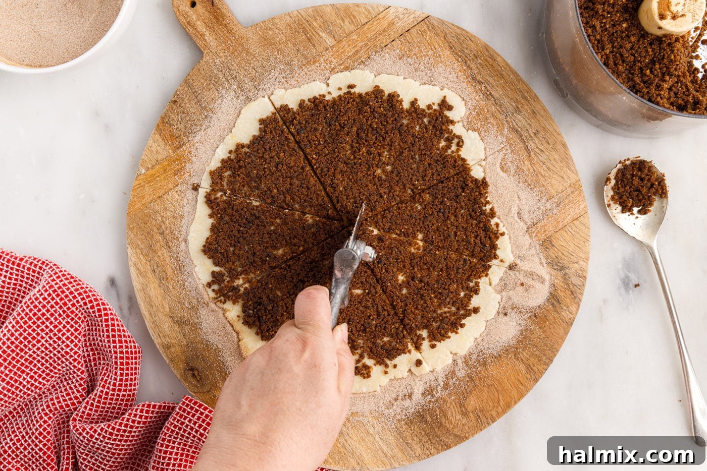 A pizza cutter is used to precisely cut the circular rugelach dough into 8 equal wedges, similar to slicing a pizza.