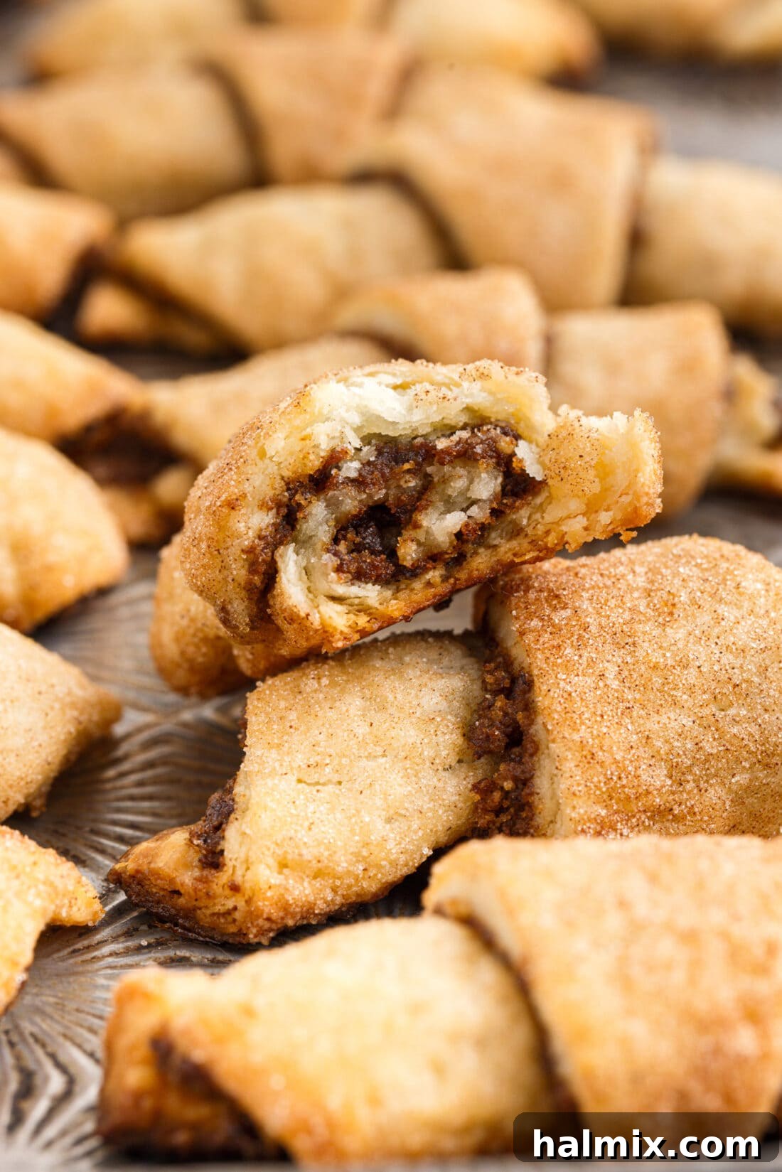 A close-up of a single Rugelach cookie with a bite taken out, revealing the delicious walnut and raisin filling.