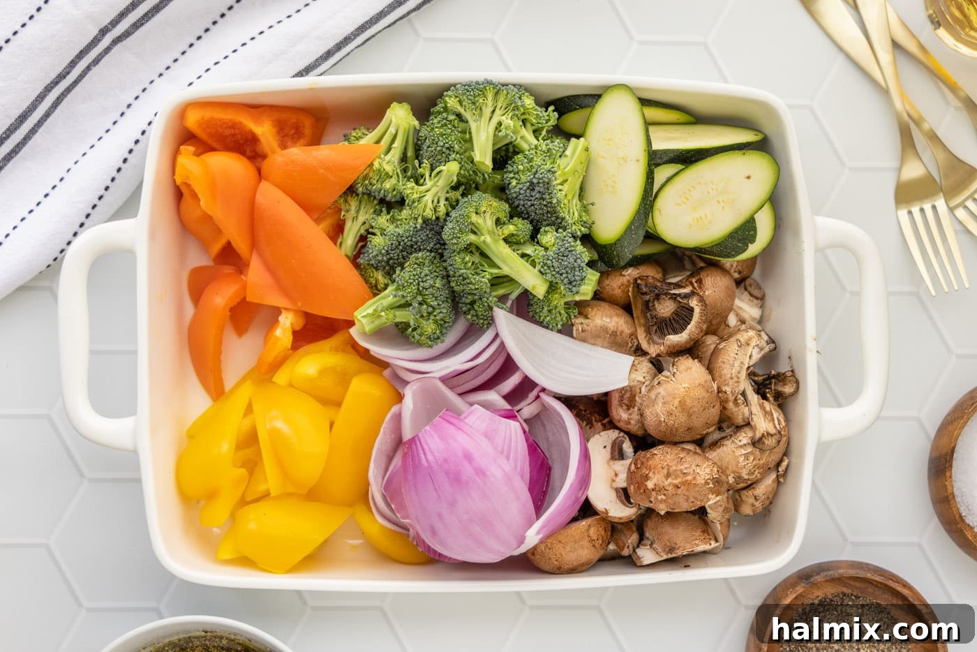 Flame-Kissed Veggie Delights 5 Assortment of prepped vegetables including onion, bell pepper, mushrooms, zucchini, and broccoli cut in a baking dish