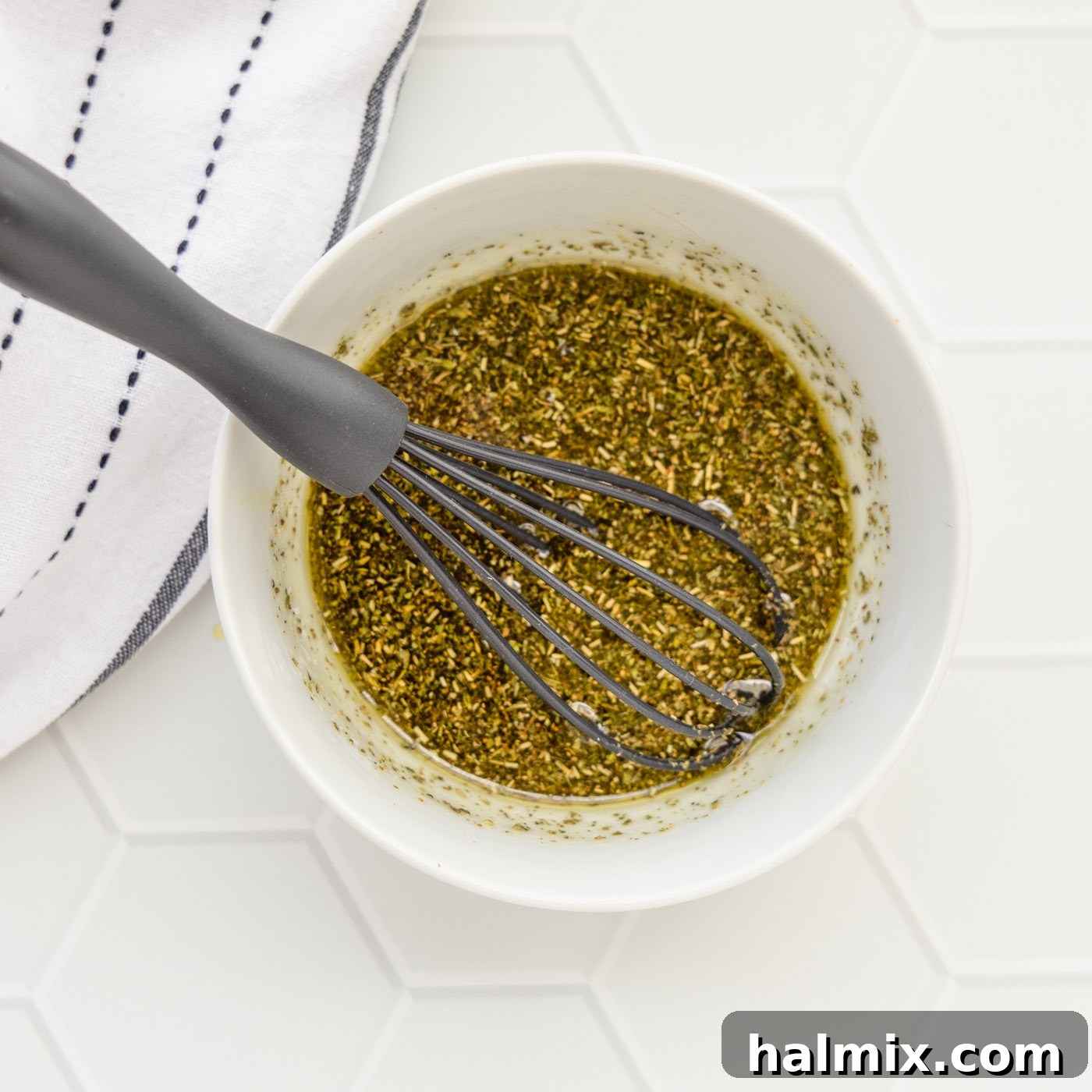 Bowl containing whisked olive oil and seasonings for vegetables