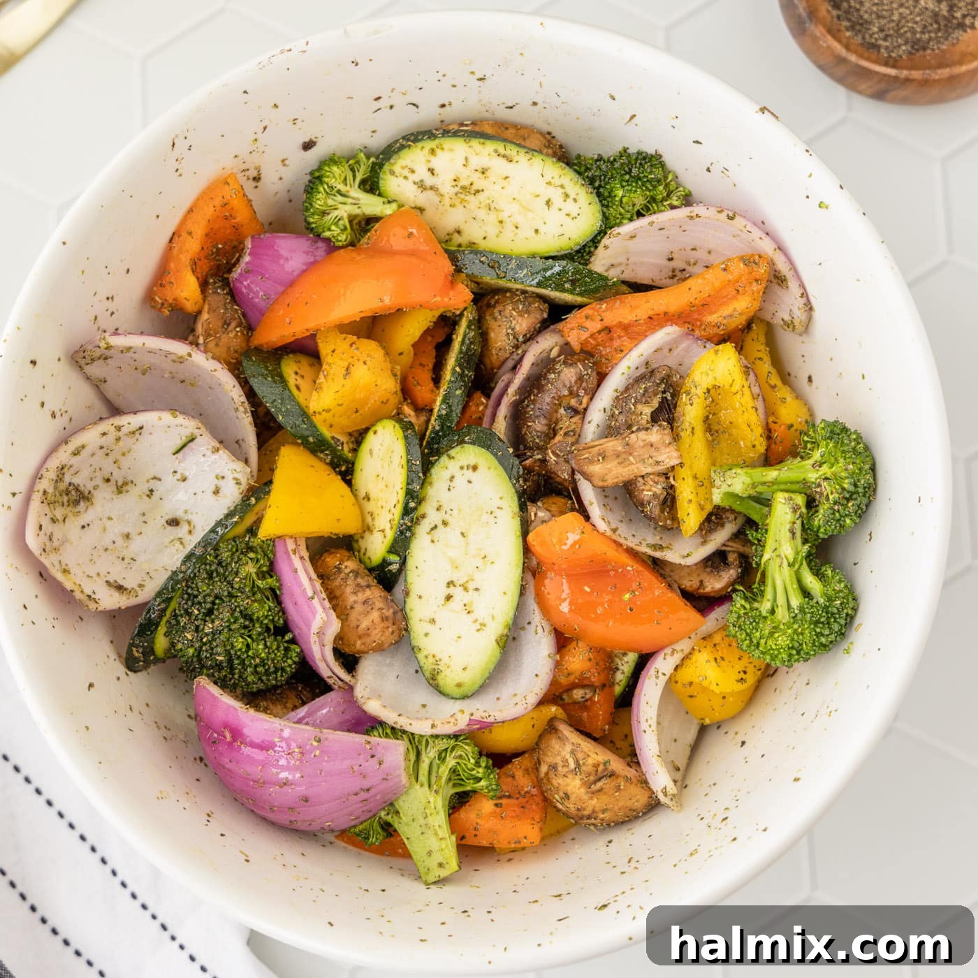 Grilled vegetables tossed with olive oil and seasoning in a large bowl