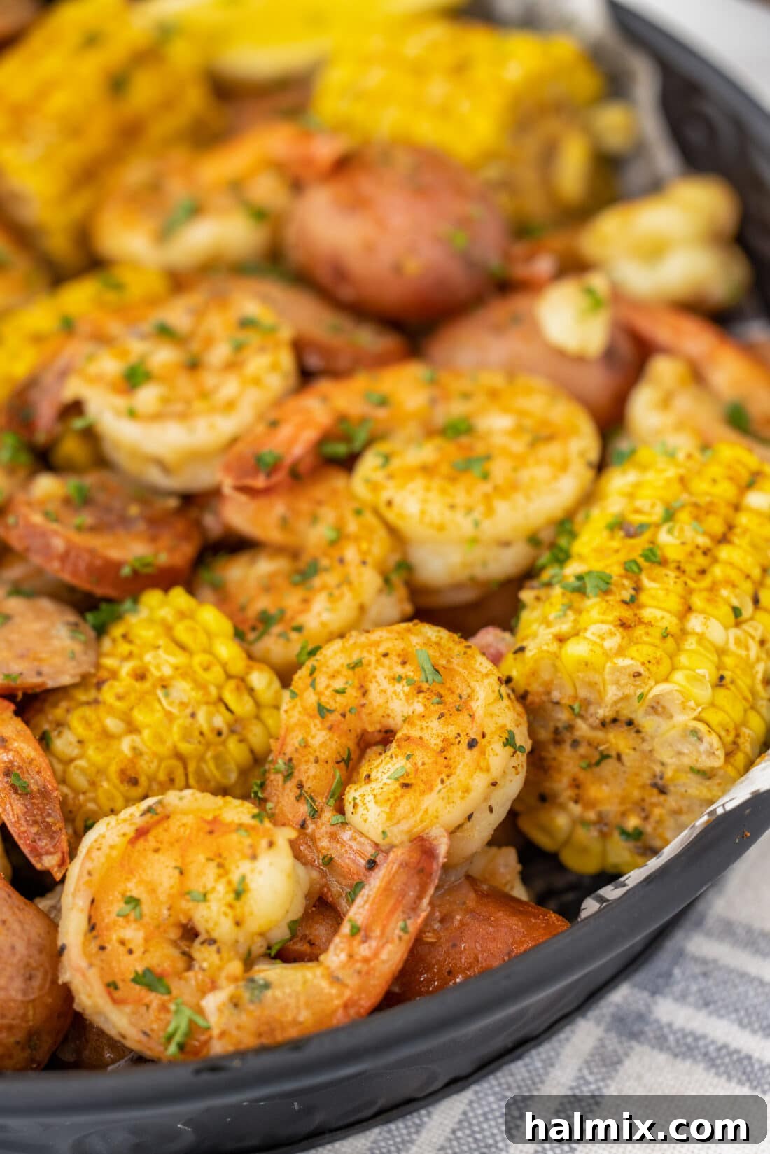 A close-up shot of a steaming Southern Shrimp Boil, showing off the vibrant red shrimp, yellow corn, and savory sausage pieces.