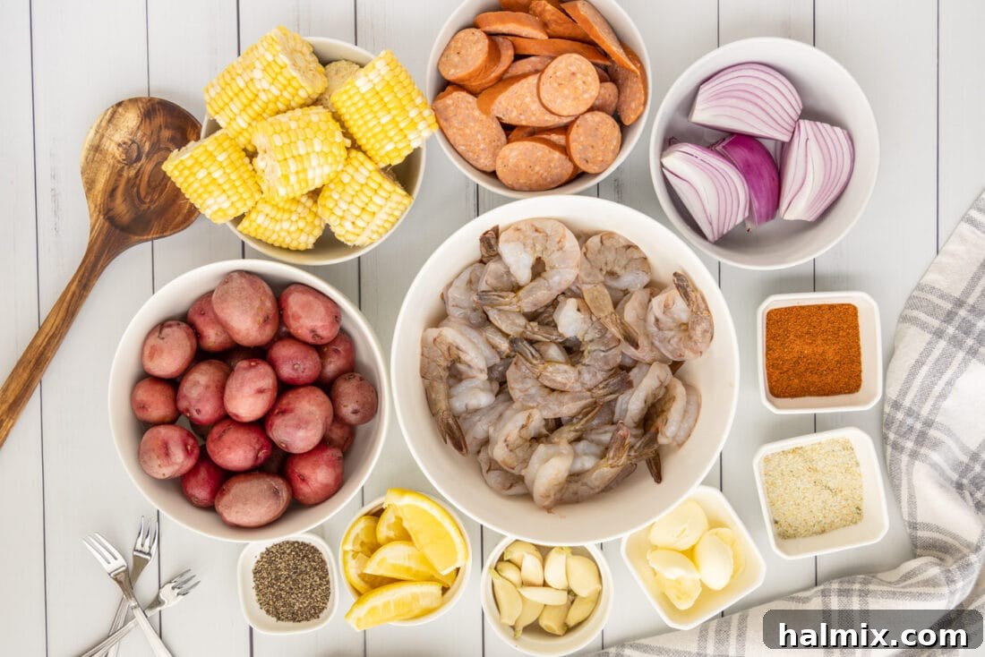 An array of fresh ingredients for a Southern Shrimp Boil, including raw shrimp, corn, potatoes, sausage, and seasonings, laid out on a wooden board.