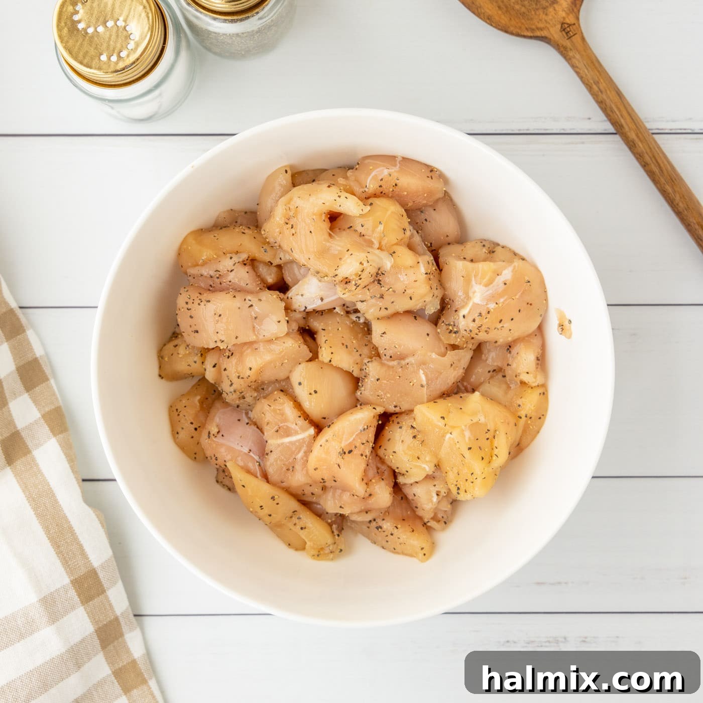 Cubed chicken seasoned with salt and pepper in a bowl