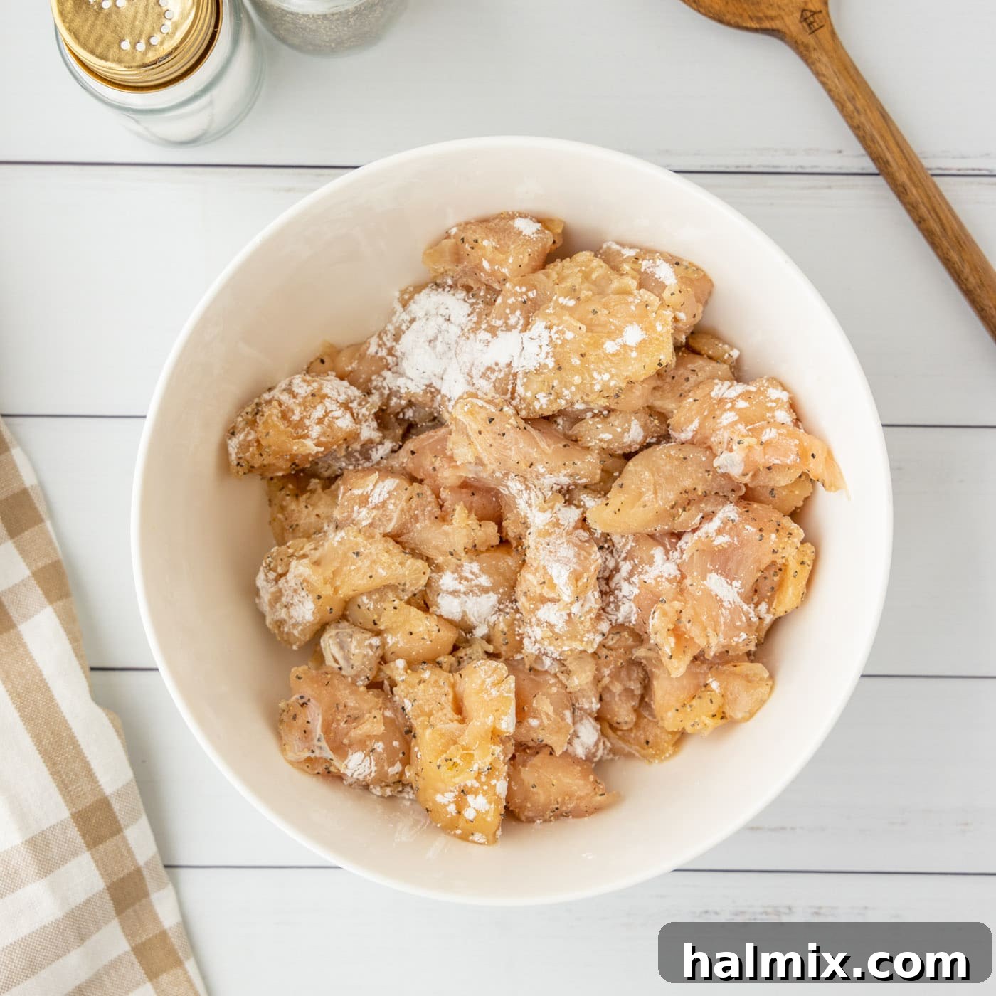 Cornstarch sprinkled on top of cubed chicken in a bowl