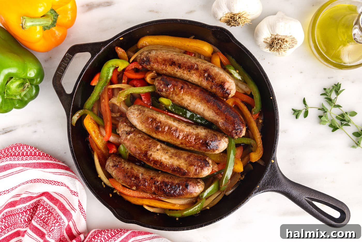 sausage and peppers finishing cooking in a skillet in the oven