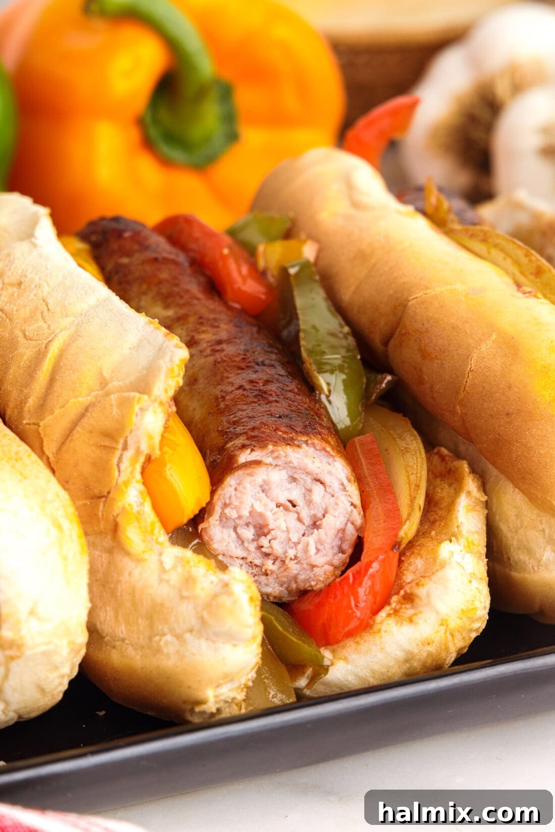 Sausage and Peppers on a bun with a bite taken out, showing the rich filling