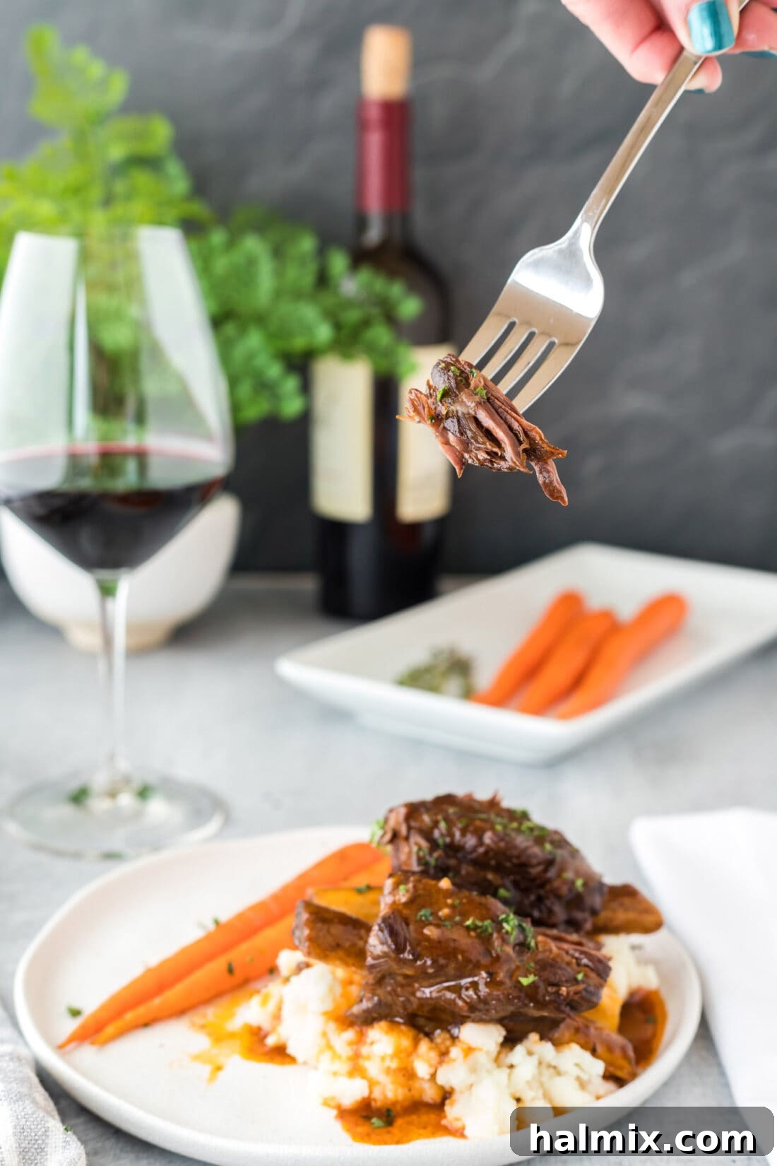 A fork lifting a piece of Instant Pot Beef Short Ribs from a plate